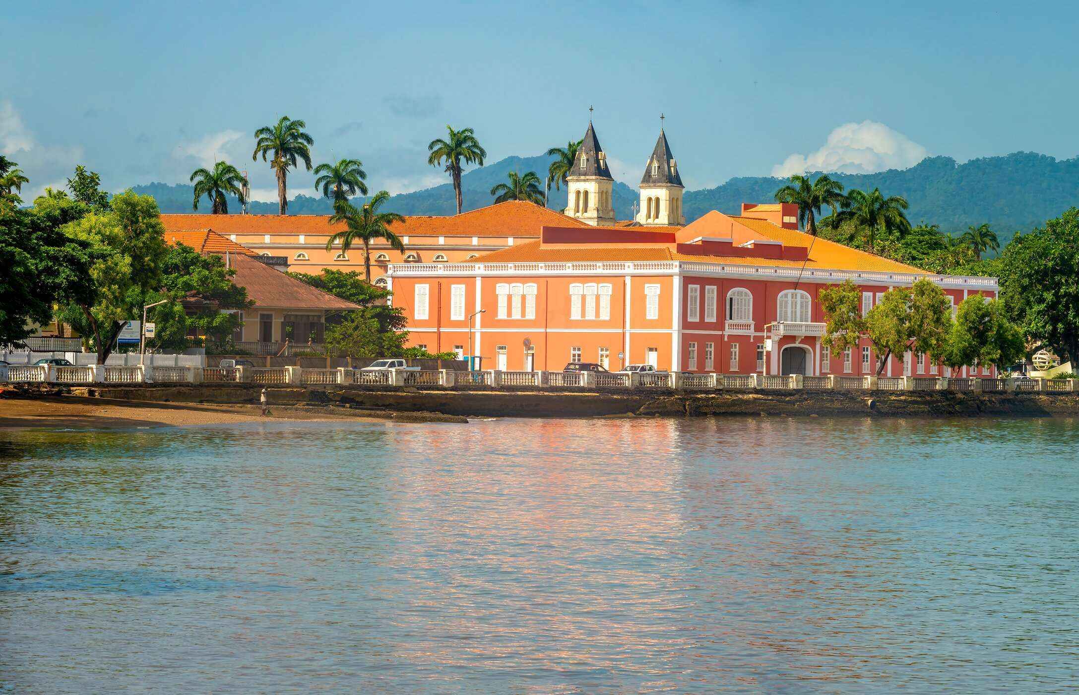 Vista panorámica de un edificio histórico en Santo Tomé y Príncipe con fachadas naranjas, situado frente al mar.