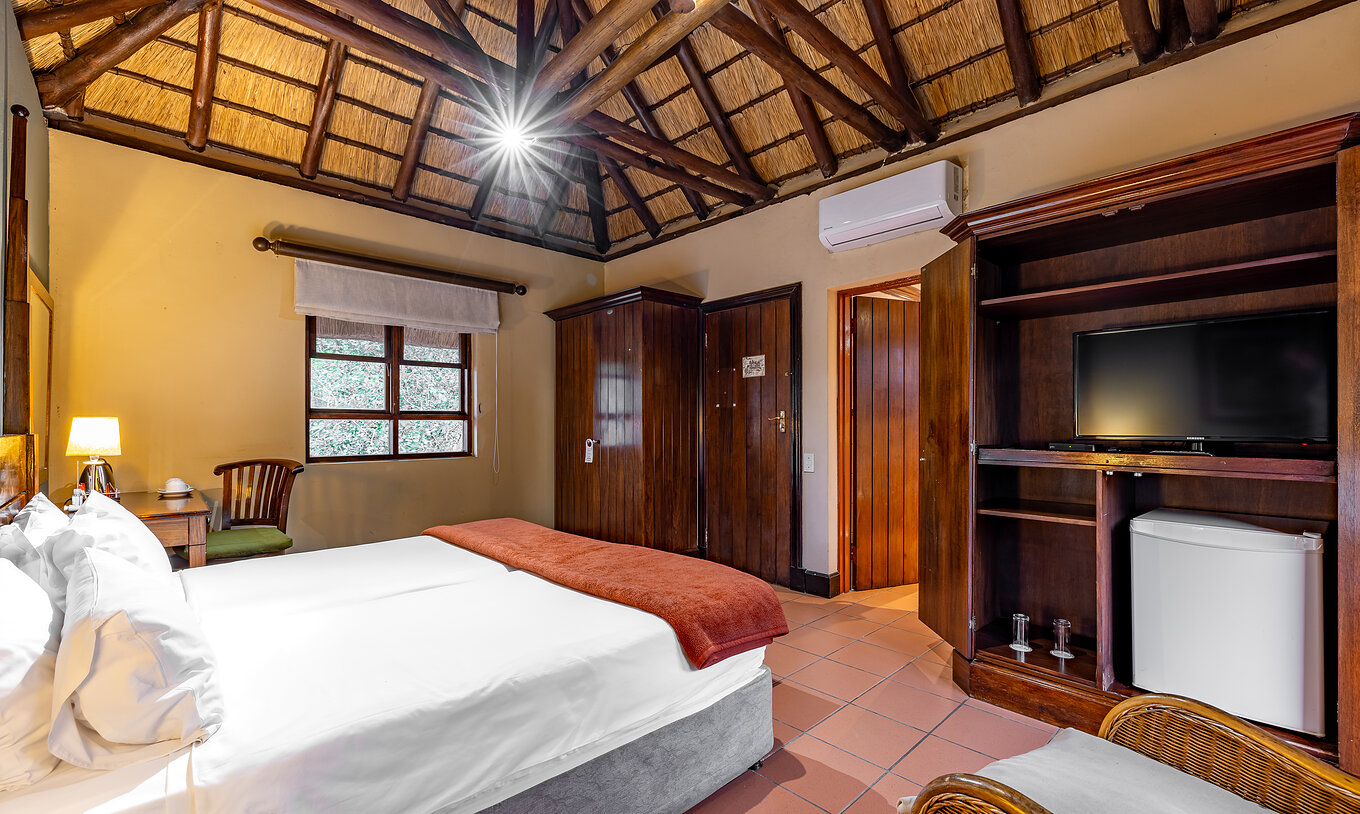 El Quarto Standard del Pestana Kruger Lodge tiene dos camas, aire acondicionado, televisor y decoración en madera