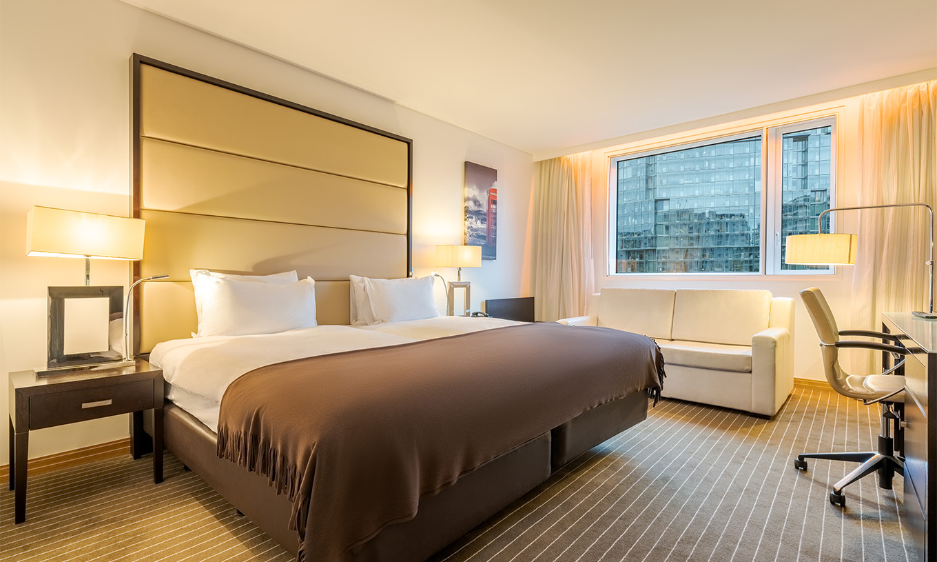 El Twin Deluxe del Pestana Chelsea Bridge tiene dos camas juntas, mesita, sofá, lámparas y ventanas con cortinas