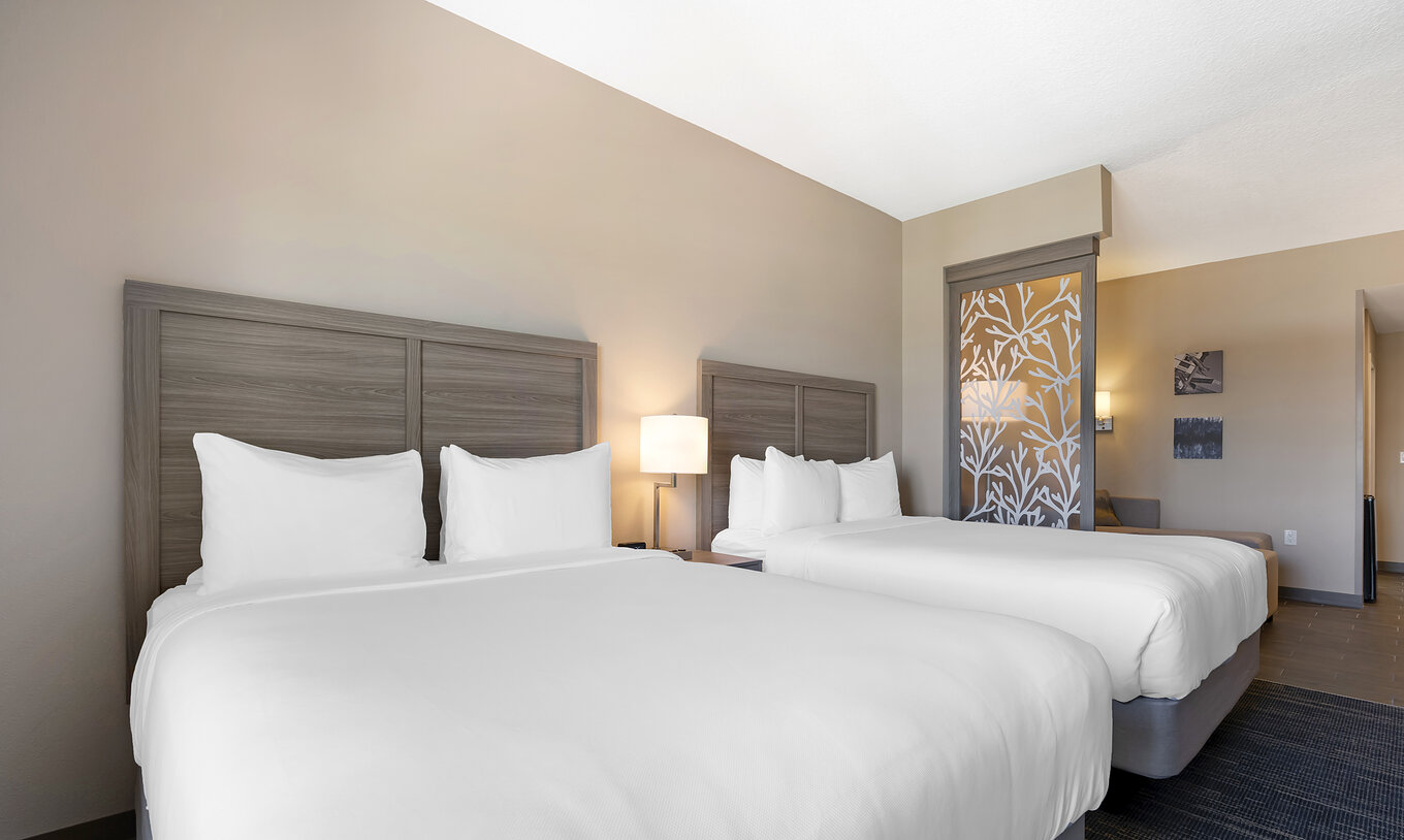 La Suite Doble Queen del Pestana Orlando Suites Lake Buena Vista tiene dos camas matrimoniales y mesa de noche con lámpara