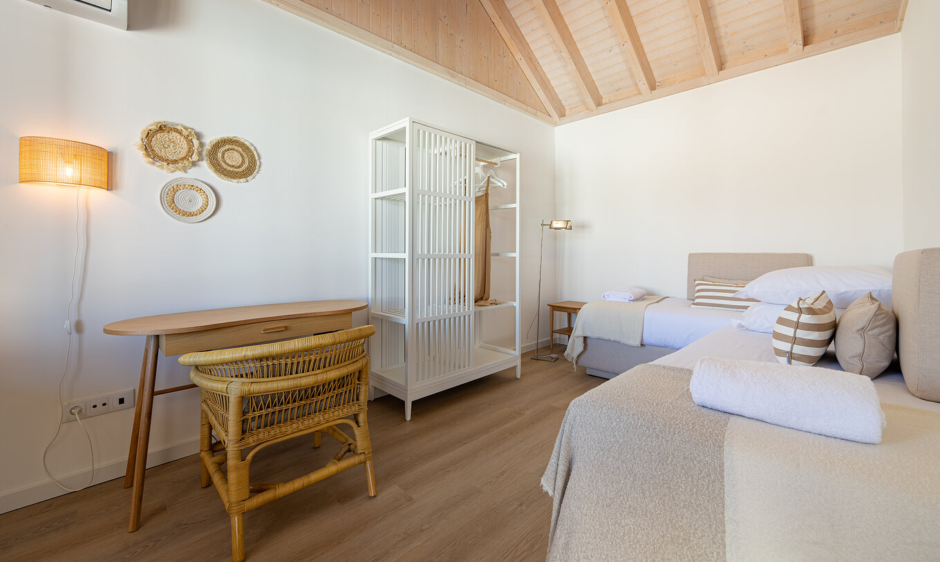 La Standard Villa de Pestana Comporta Village Residences tiene un dormitorio con cama, mesa y silla de mimbre