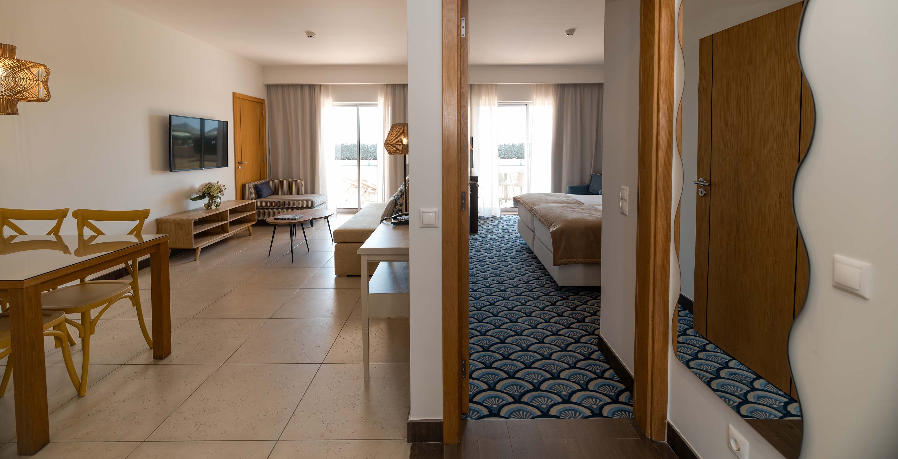 Apartamento T1 Vista Jardín en Pestana Alvor Beach Villas tiene una sala con sofá, TV y ventana con balcón