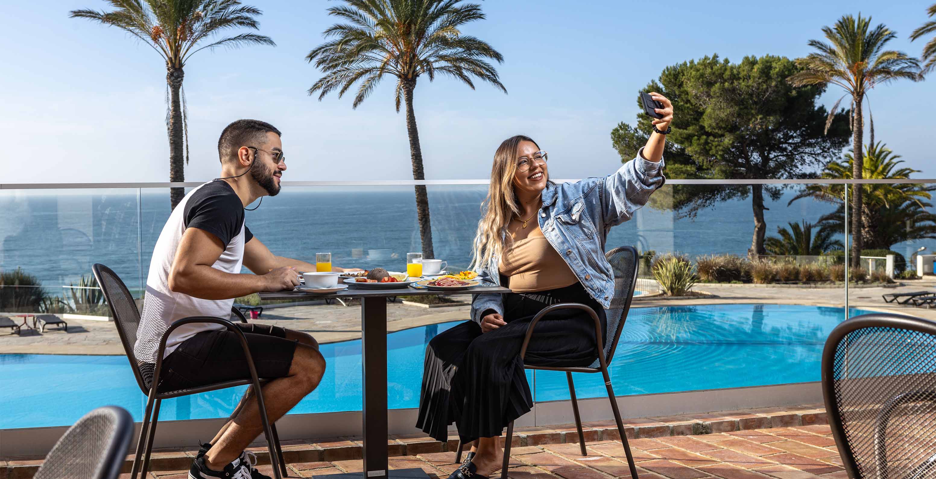 Pareja toma una selfie mientras desayuna en la terraza del restaurante del Pestana Alvor Praia, con vista al mar