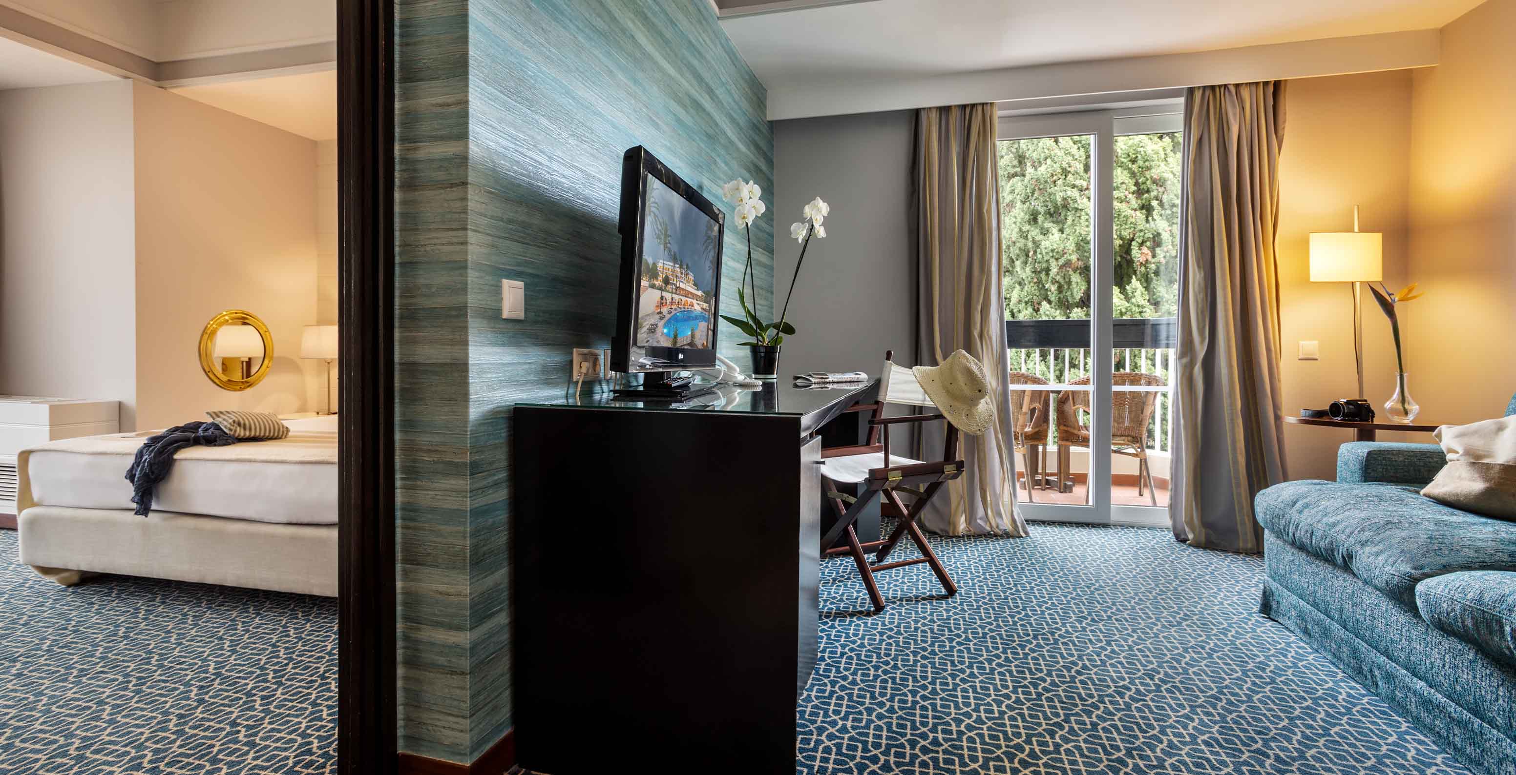 La Suite Vista Jardín del Pestana Alvor Praia tiene división entre sala con sofá, televisión y habitación con cama