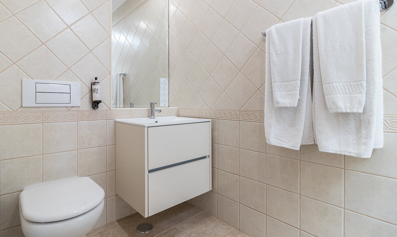 El apartamento de dos dormitorios en Pestana Gramacho tiene baño elegante con toallas blancas y luz natural suave