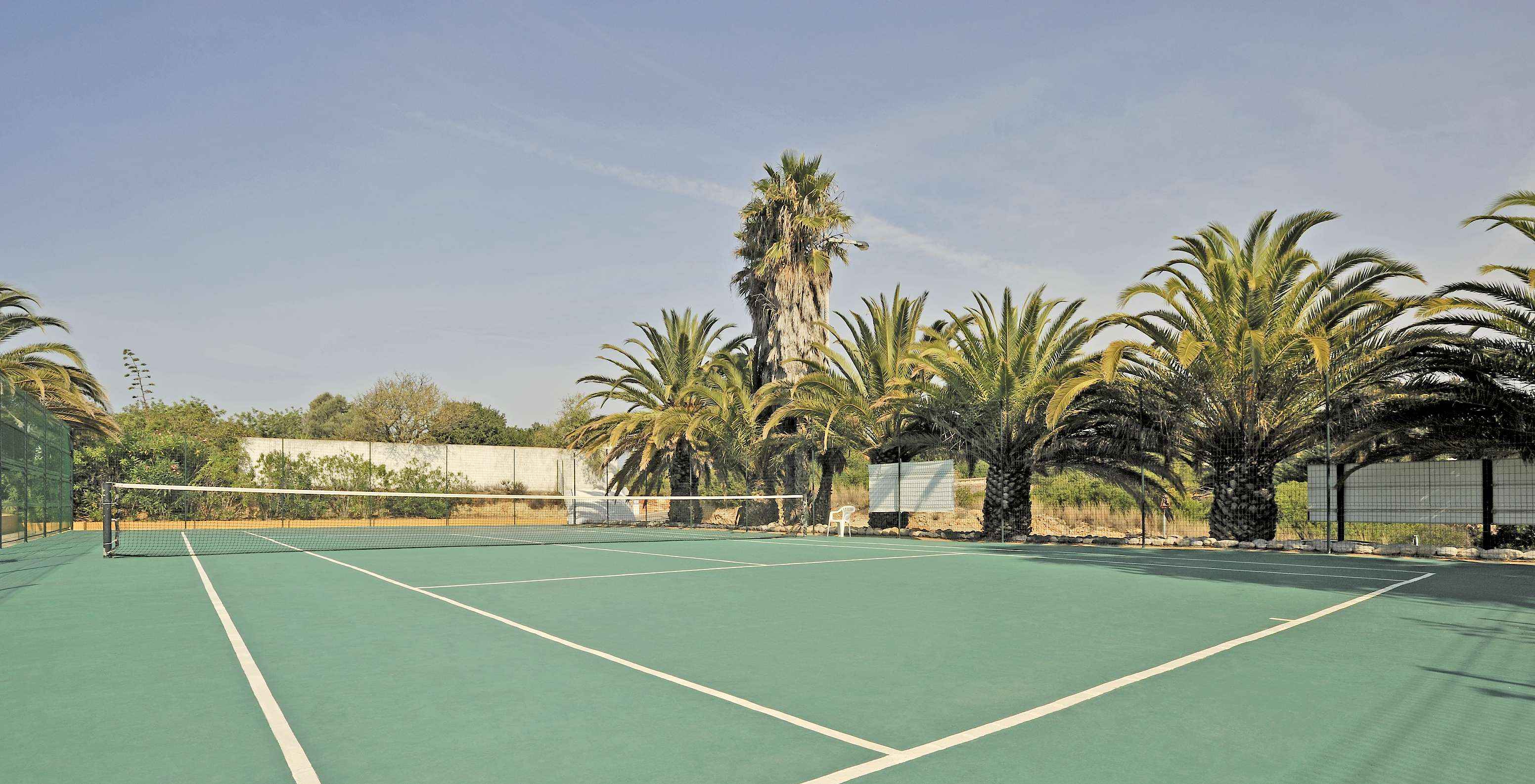 Campo de tenis de superficie dura en Pestana Palm Gardens, rodeado de palmeras