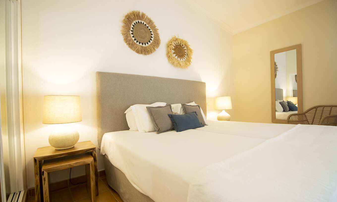 El Apartamento T2 Standard del Pestana Palm Gardens tiene una cama de casal con almohadas decorativas y cuadros decorativos