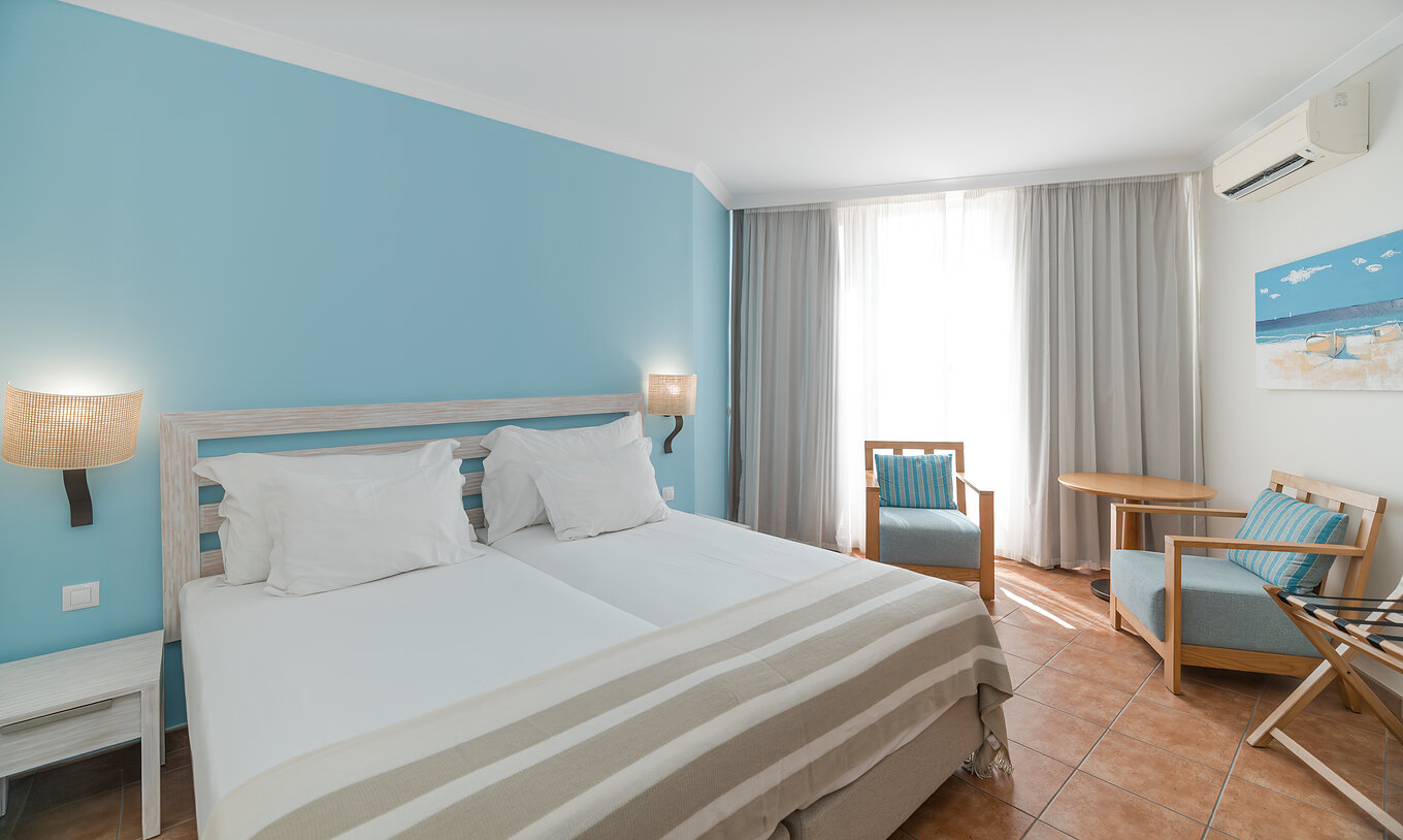 El Deluxe Vista Mar del Pestana Viking tiene dos camas, mesa de noche, dos sillones y aire acondicionado