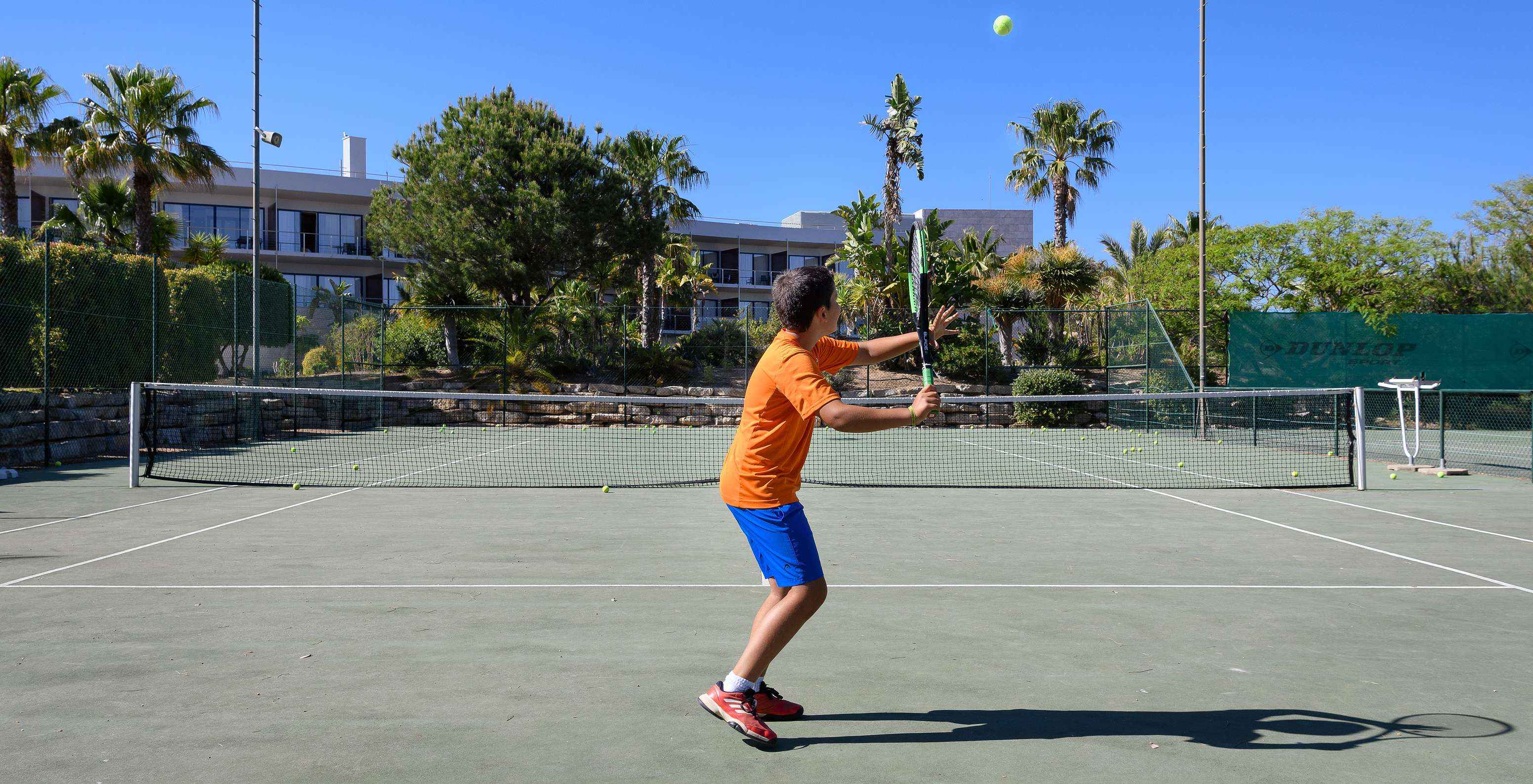 Niño jugando al tenis en la cancha del Pestana Vila Sol - Vilamoura, Hotel con Golf y Spa en el Algarve