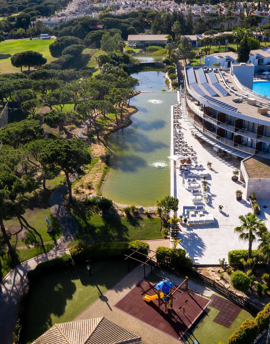 Vista de Pestana Vila Sol - Vilamoura, un hotel de 5 estrellas en Vilamoura con piscina, rodeado de un lago y vegetación