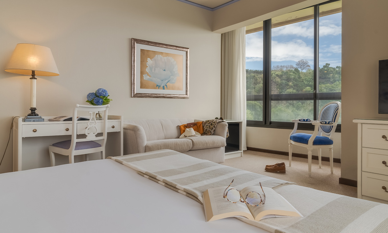 El Standard Vista Mar del Pestana Bahia Praia tiene un escritorio, un sofá y una silla cerca de la ventana con vista jardín