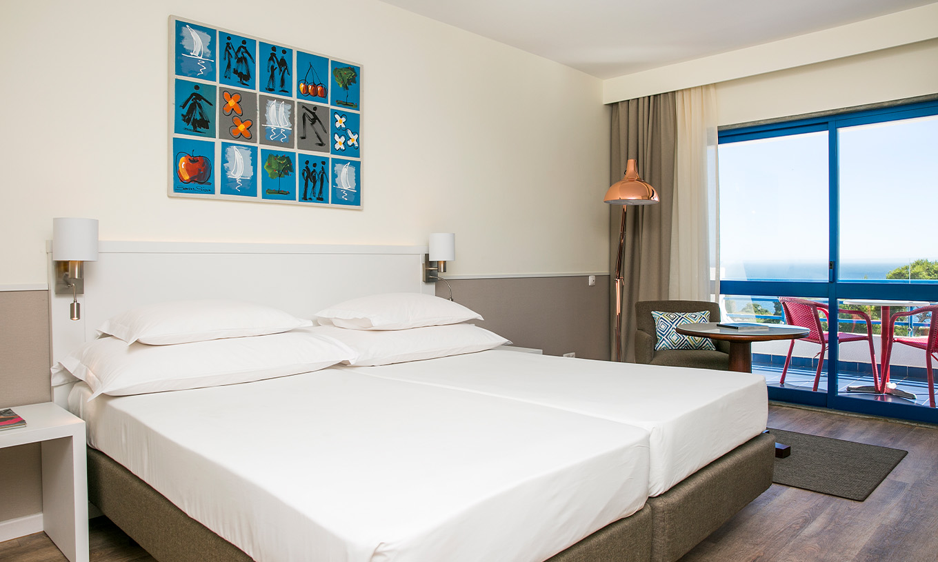 La Habitación Deluxe Vista Mar del Pestana Cascais cuenta con dos camas individuales, lámparas y un sillón con mesa