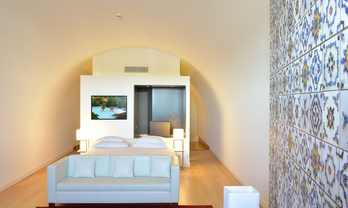 La Junior Suite Art District del Pestana Cidadela Cascais tiene una cama doble con sofá blanco y un cuadro en la pared