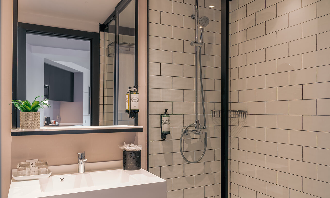 El Double Deluxe Studio del Pestana Lisboa Vintage tiene una ducha con puertas de vidrio y detalles negros, y un lavabo