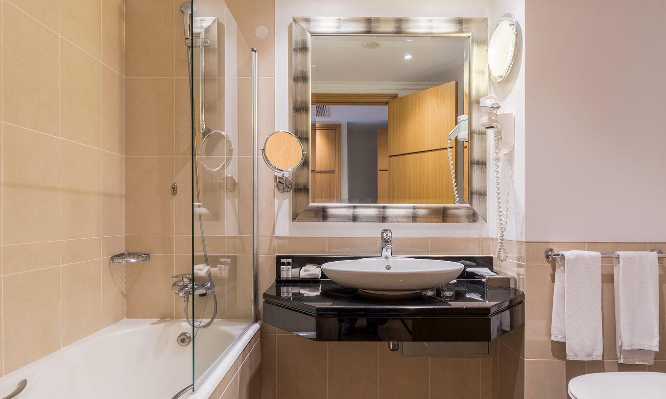 El cuarto Twin Superior Vista Mar del Pestana Grand tiene un baño con lavamanos, bañera con ducha y toalla