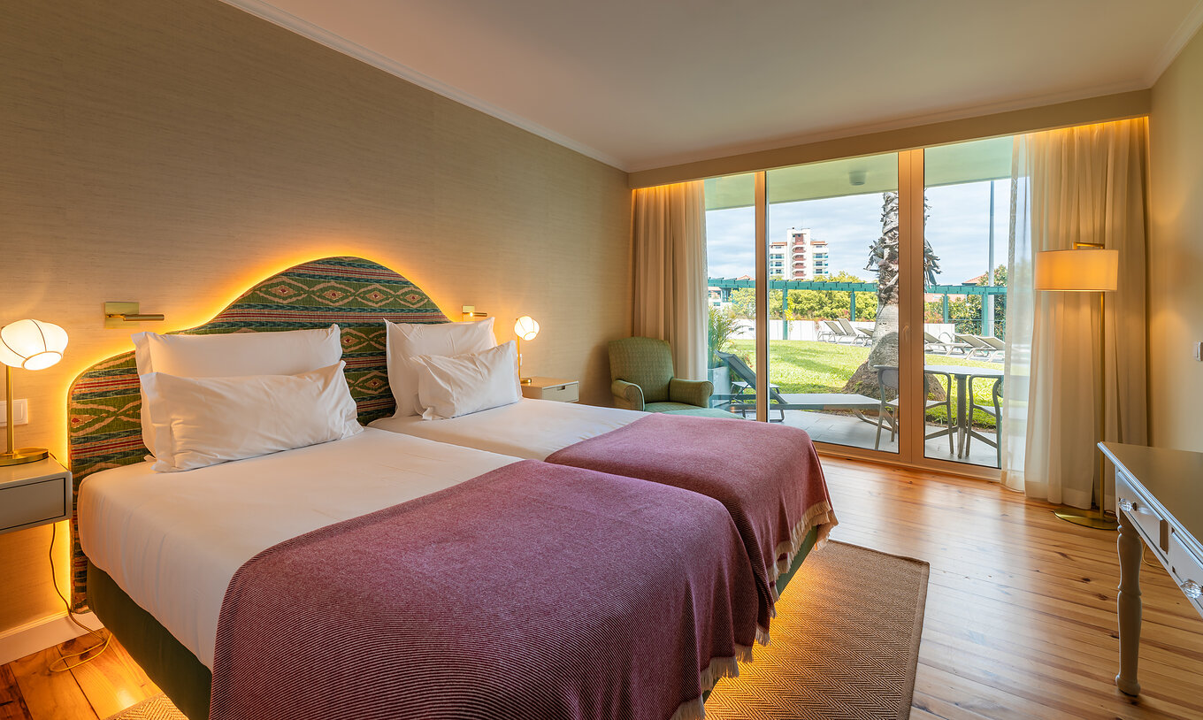 La Habitación Vista Piscina del Pestana Quinta Perestrello tiene una cama doble, un sillón y balcón con vistas al jardín.