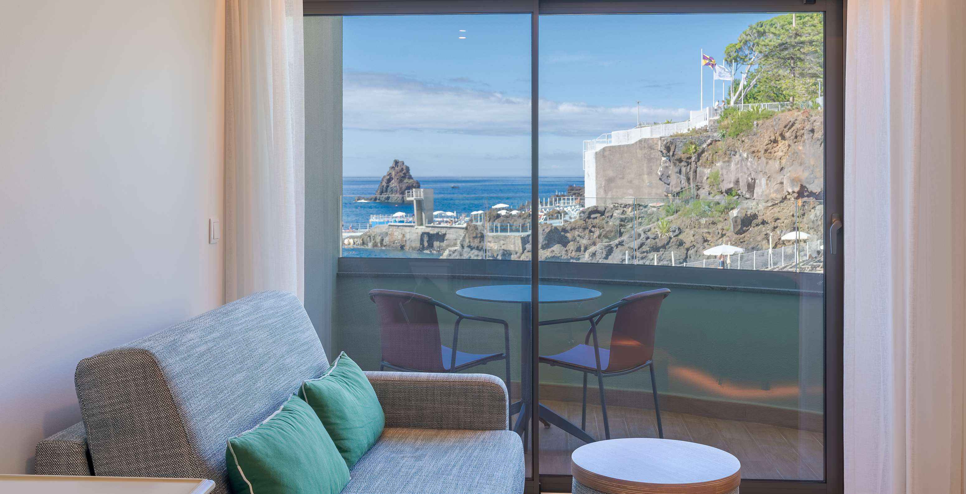 El Clásico Vista Mar Lateral del Pestana Vila Lido Madeira tiene un sofá al lado del balcón con vista lateral al mar