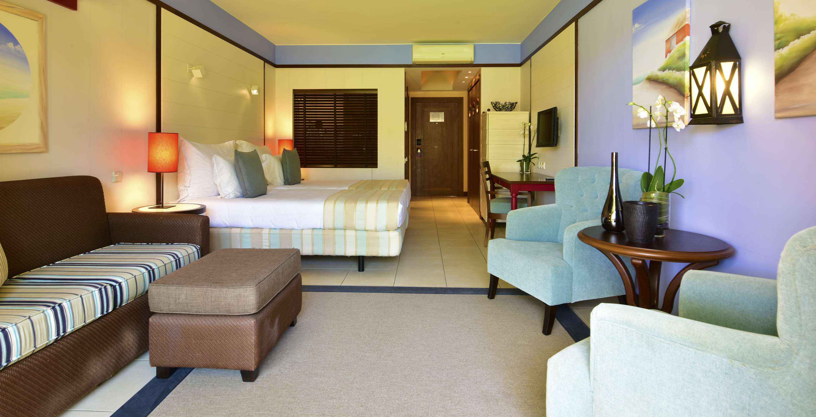 El Doble Vista Piscina del Pestana Porto Santo All Inclusive tiene un sofá, dos sillones, dos camas, televisión y escritorio