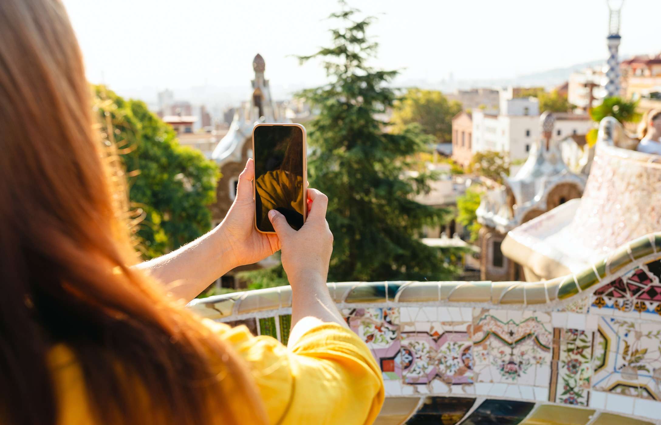 Persona fotografiando la vista de Barcelona en el famoso Parque Güell con su móvil