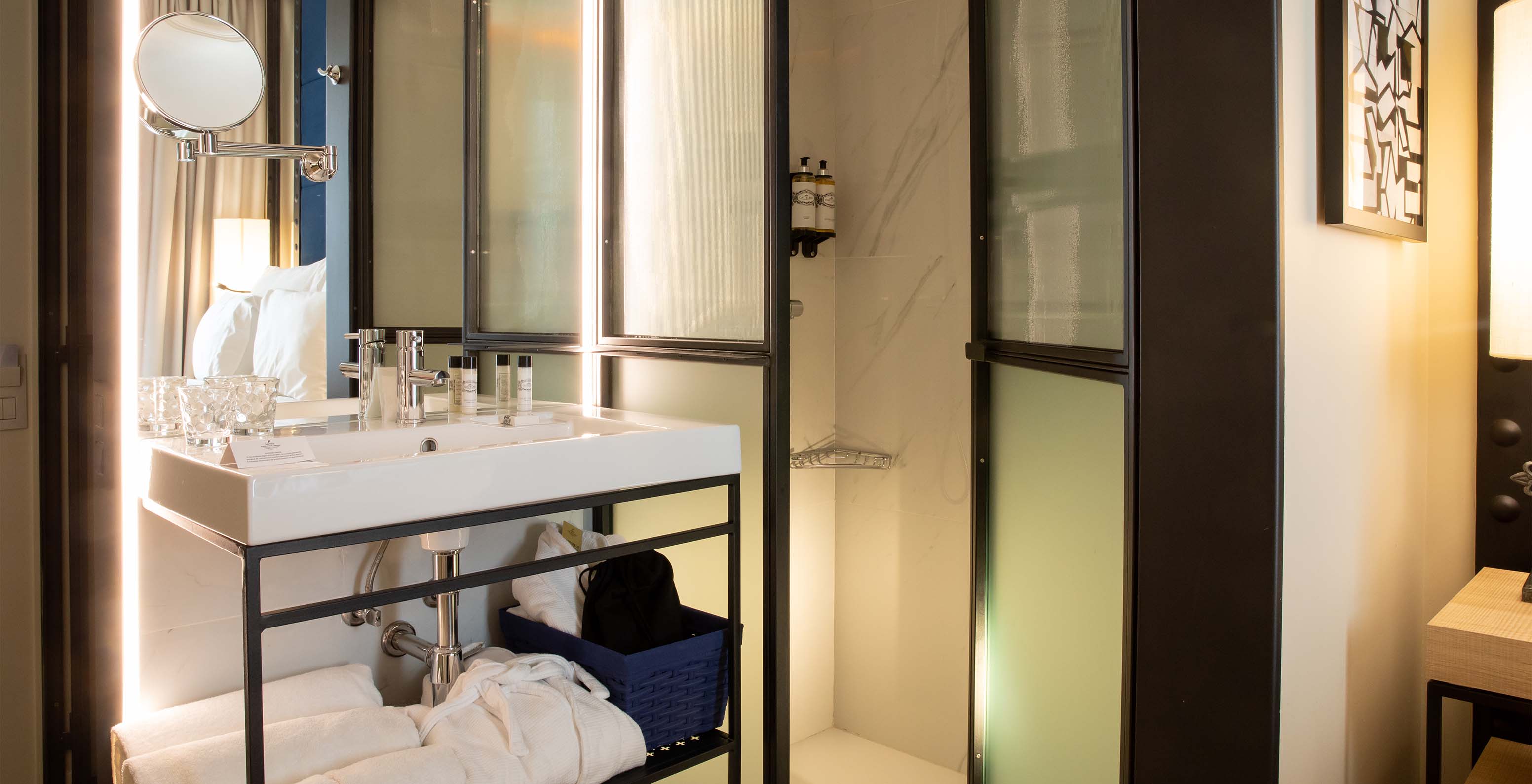 El Cuarto Clásico del Pestana Collection Plaza Mayor tiene un baño con lavabo con espejo, ducha, toallas y amenities