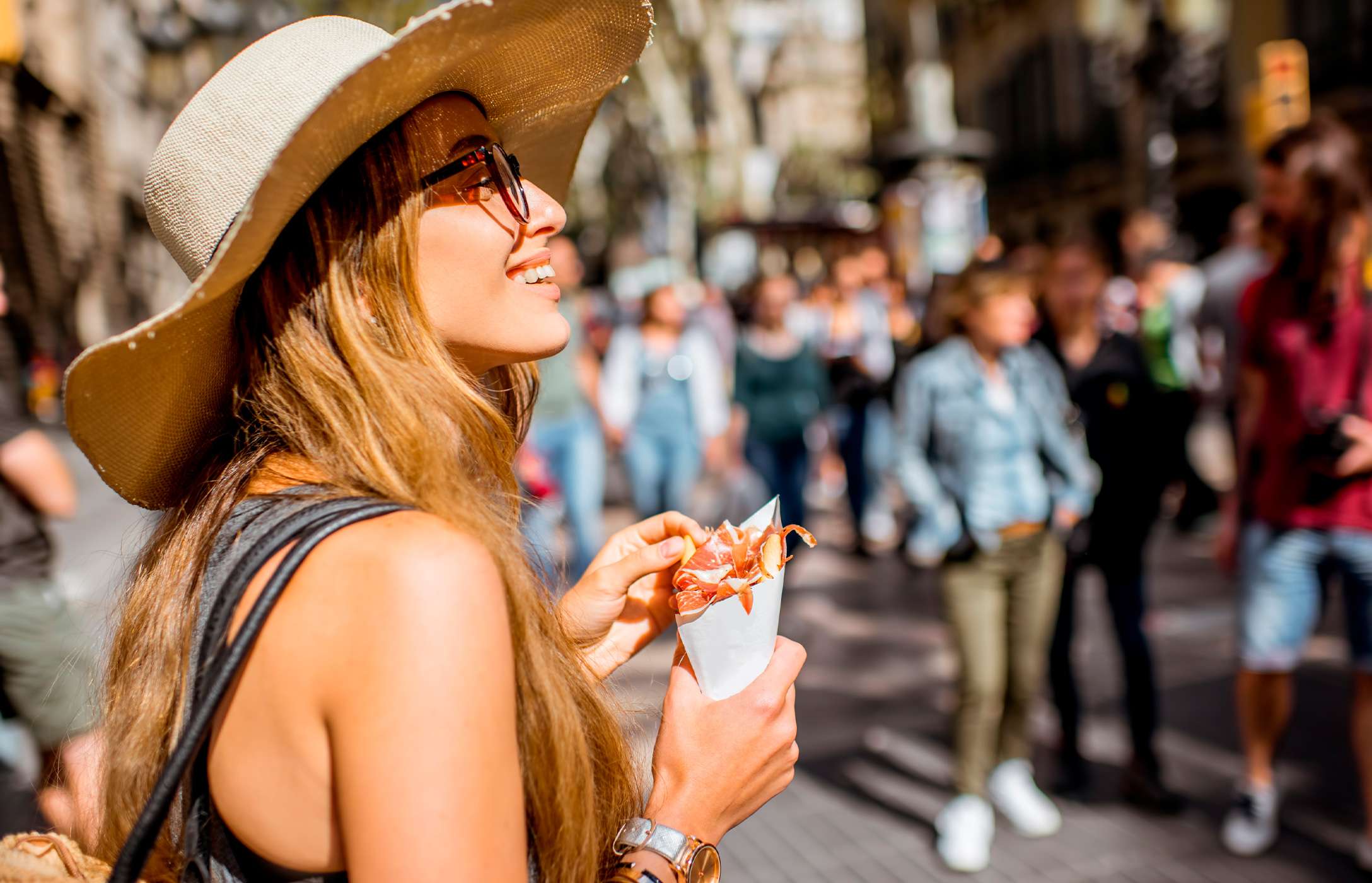 Señora visitando España, paseando por las calles mientras prueba una de las tapas tradicionales de jamón.