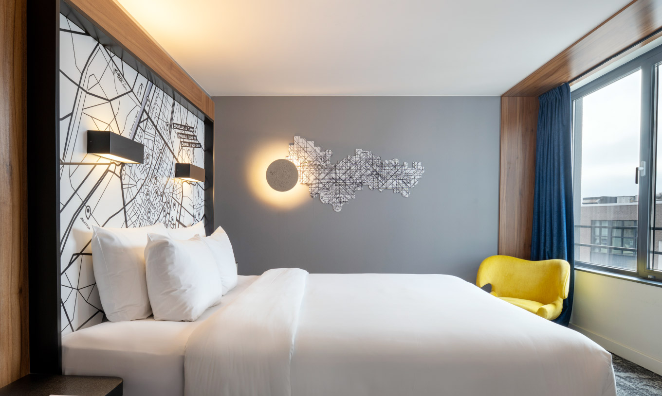 Le Standard King du Pestana Brussels Schuman dispose d'un lit double avec des draps blancs et une lampe murale