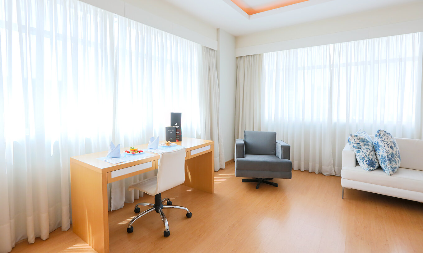 Le Deluxe Corner du Pestana Curitiba a des canapés et un bureau près de fenêtres laissant entrer beaucoup de lumière