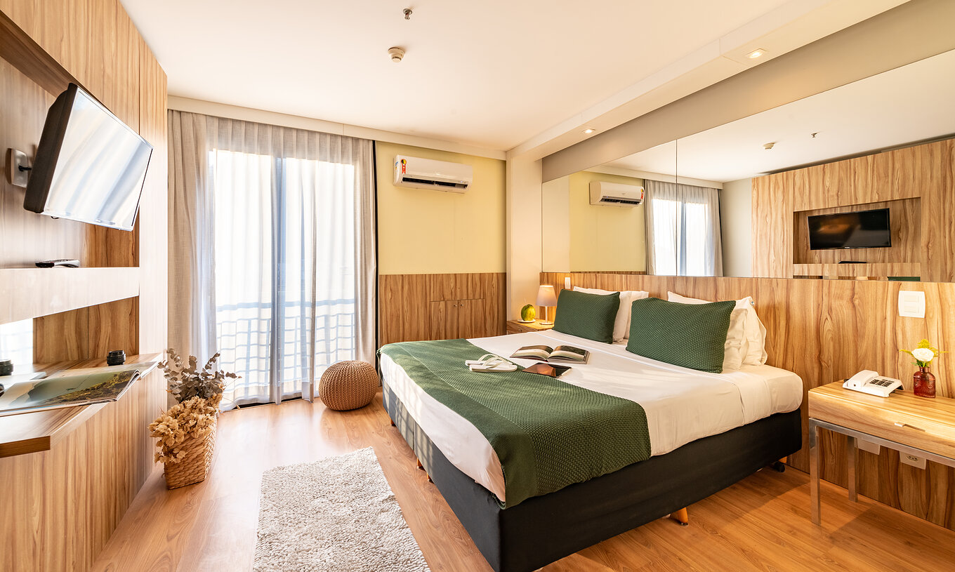 La Suite Vue Latérale Sur la Mer du Pestana Rio Atlântica a un lit double avec miroir au lit et une télévision en face