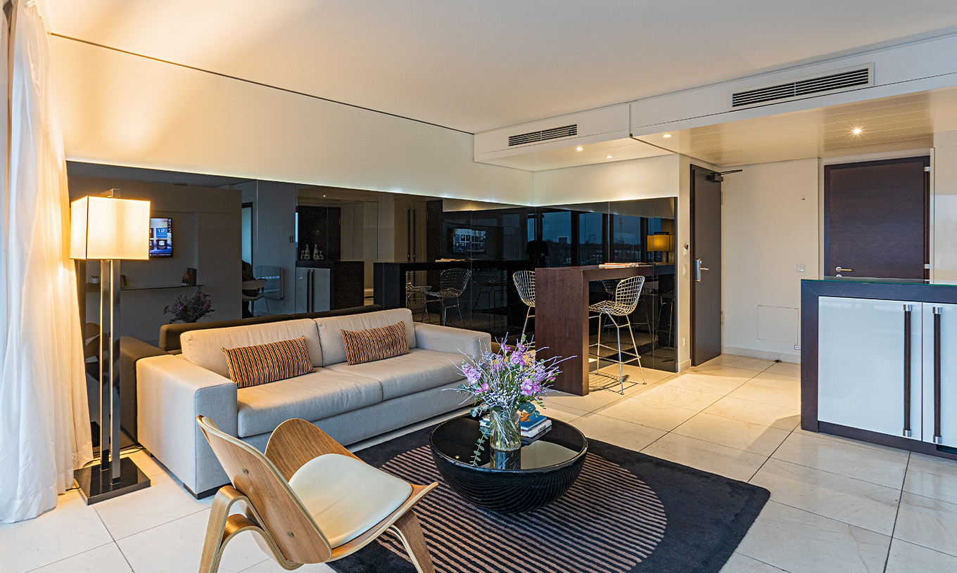 La Suite Panoramique du Pestana Berlin Tiergarten a un Canapé avec Lampe, Table Basse et un Bar avec Chaises