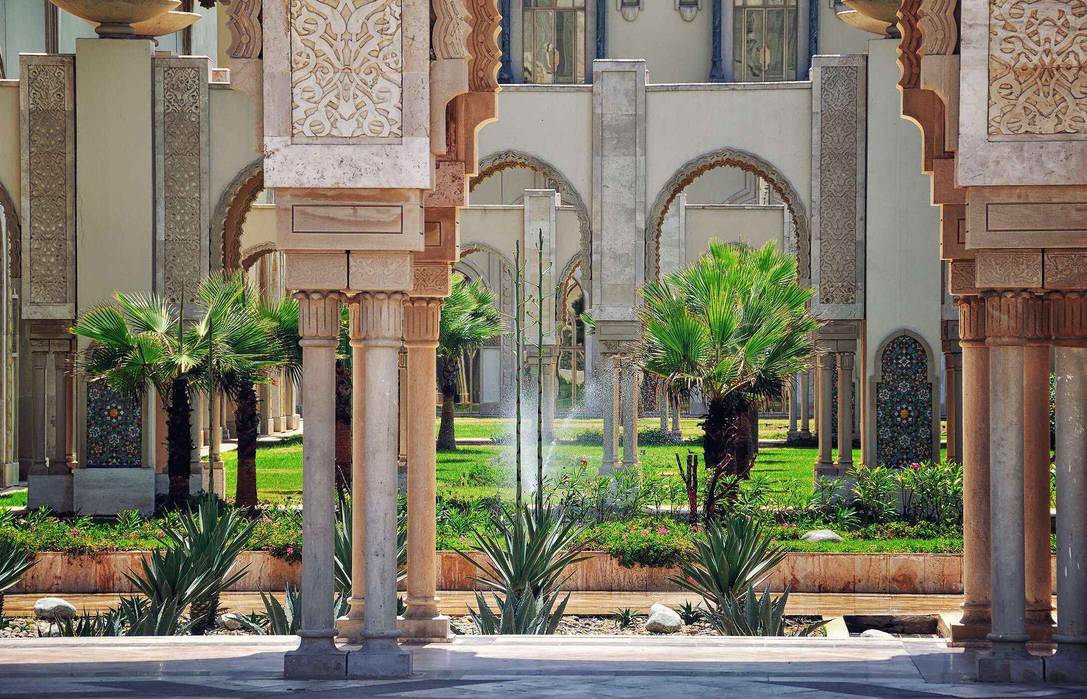 Vue intérieure des jardins de la mosquée Hassan II, remplis de pelouses et d'arbres