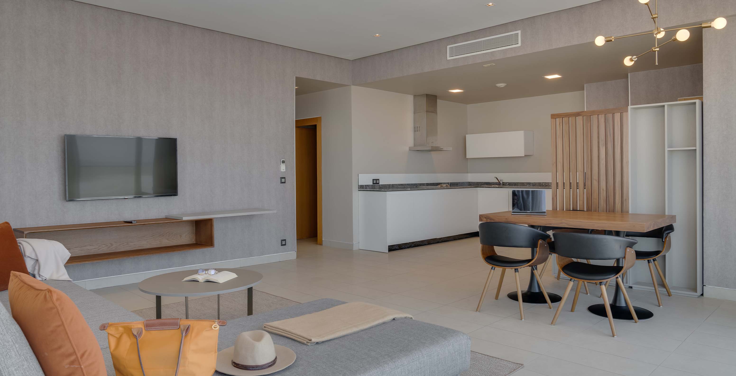 La Suite Familiale Corniche du Pestana Casablanca a un salon spacieux avec canapé, télévision, table à manger et kitchenette
