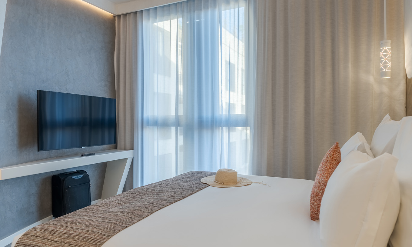 La suite du Pestana CR7 Marrakech a une chambre avec lit double, télévision et fenêtre avec rideaux
