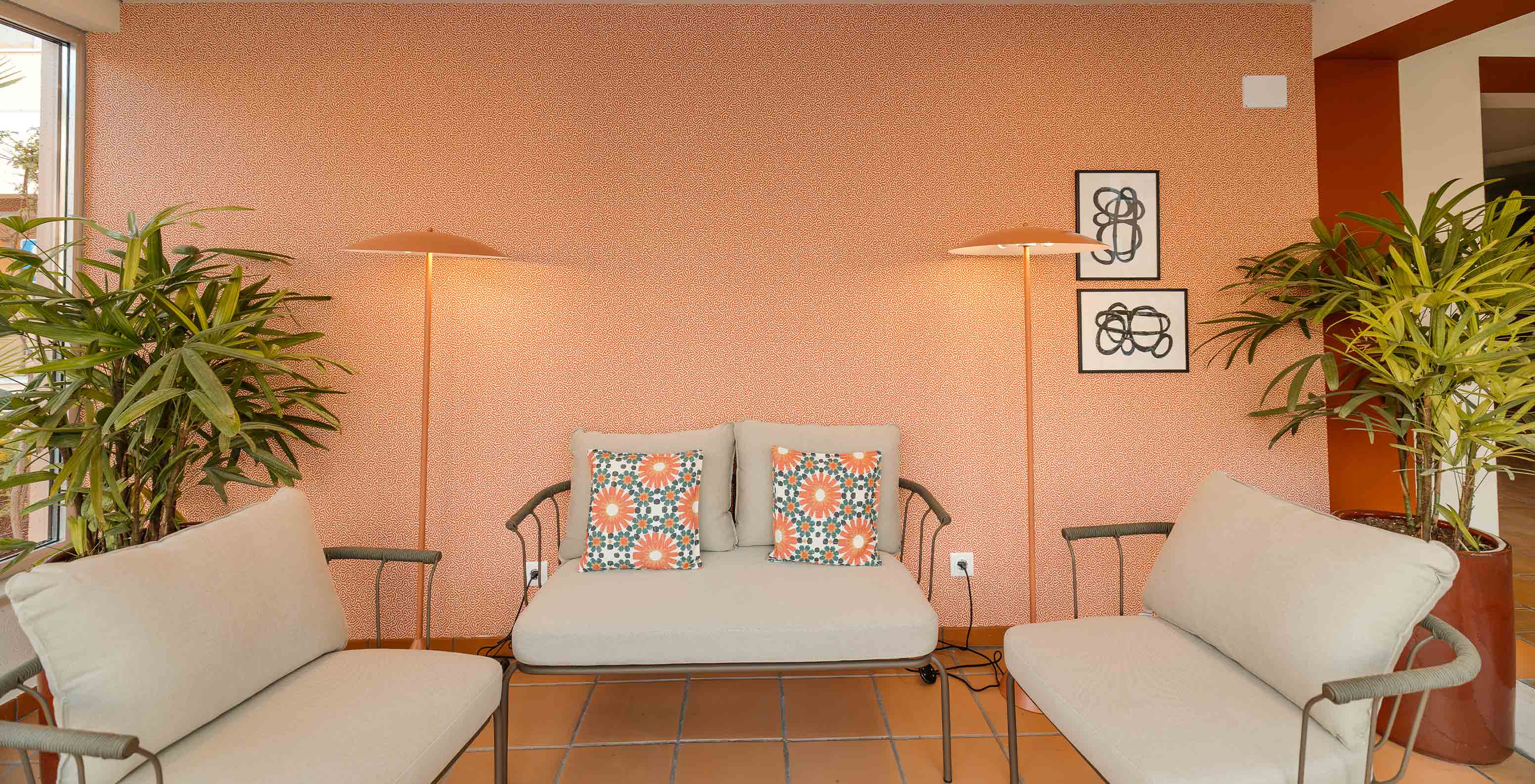 Hall de l’hôtel près de la plage avec piscine, papier peint orange et trois canapés beiges confortables