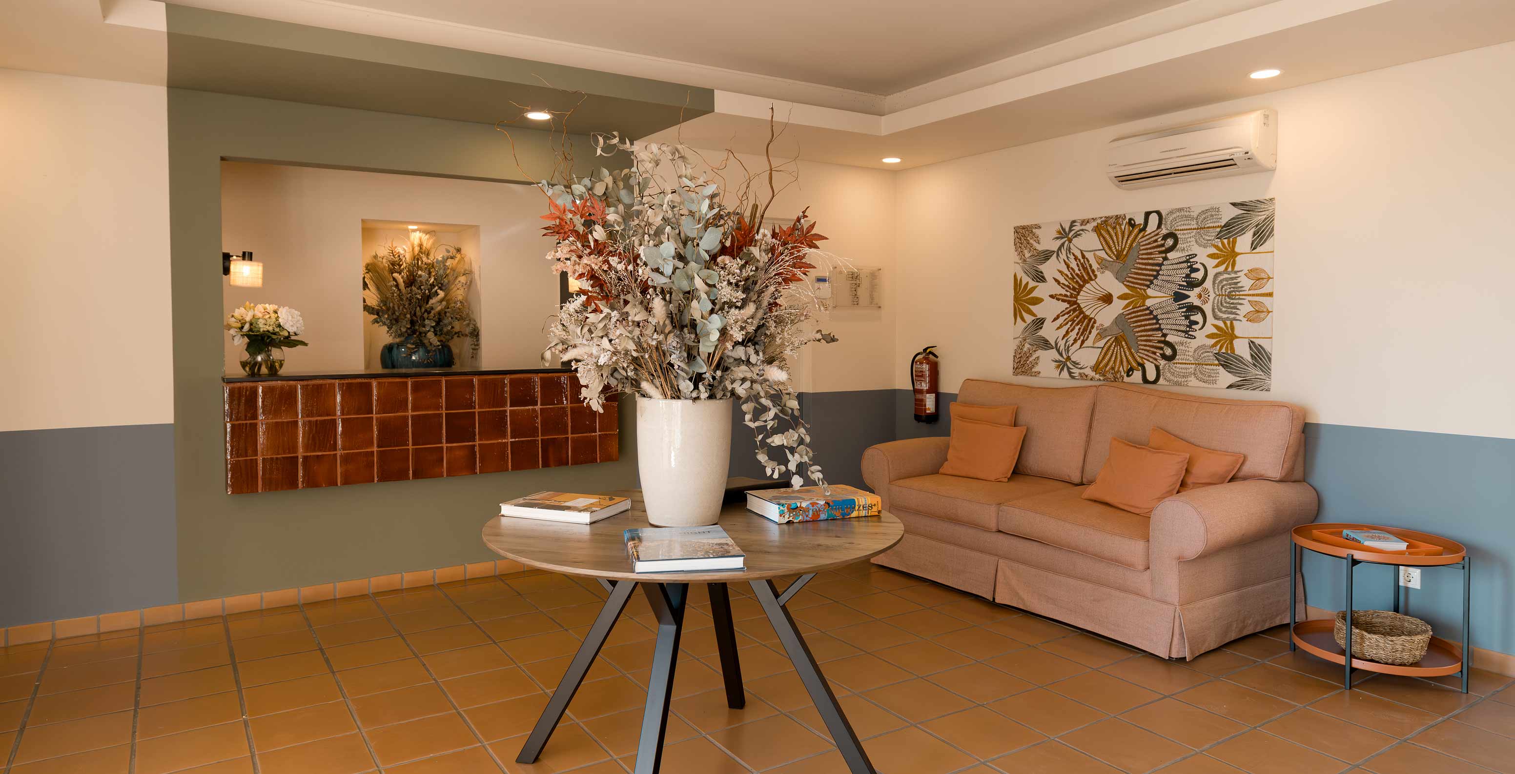 Réception de l’hôtel près de la plage avec piscine, canapé orange confortable et table d’appoint avec un vase de fleurs