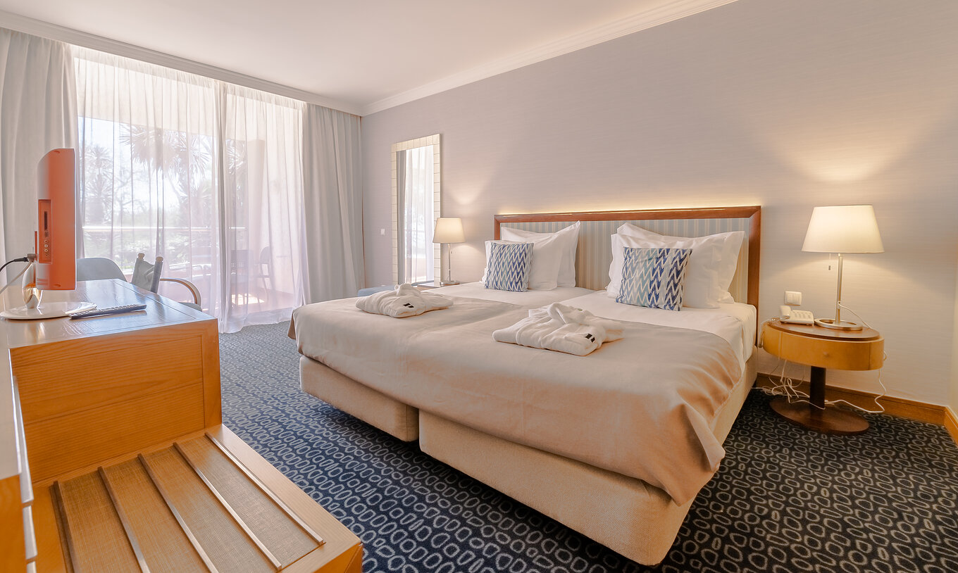 Le T1 - 1 Chambre du Pestana Alvor Park a un lit double, moquette bleue et un bureau avec télévision