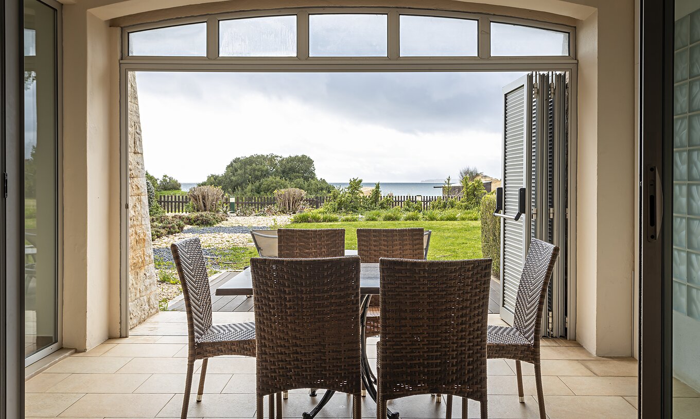 Le Cliff Family du Pestana Alvor Praia a un porche avec table, chaises et un jardin avec vue sur la plage