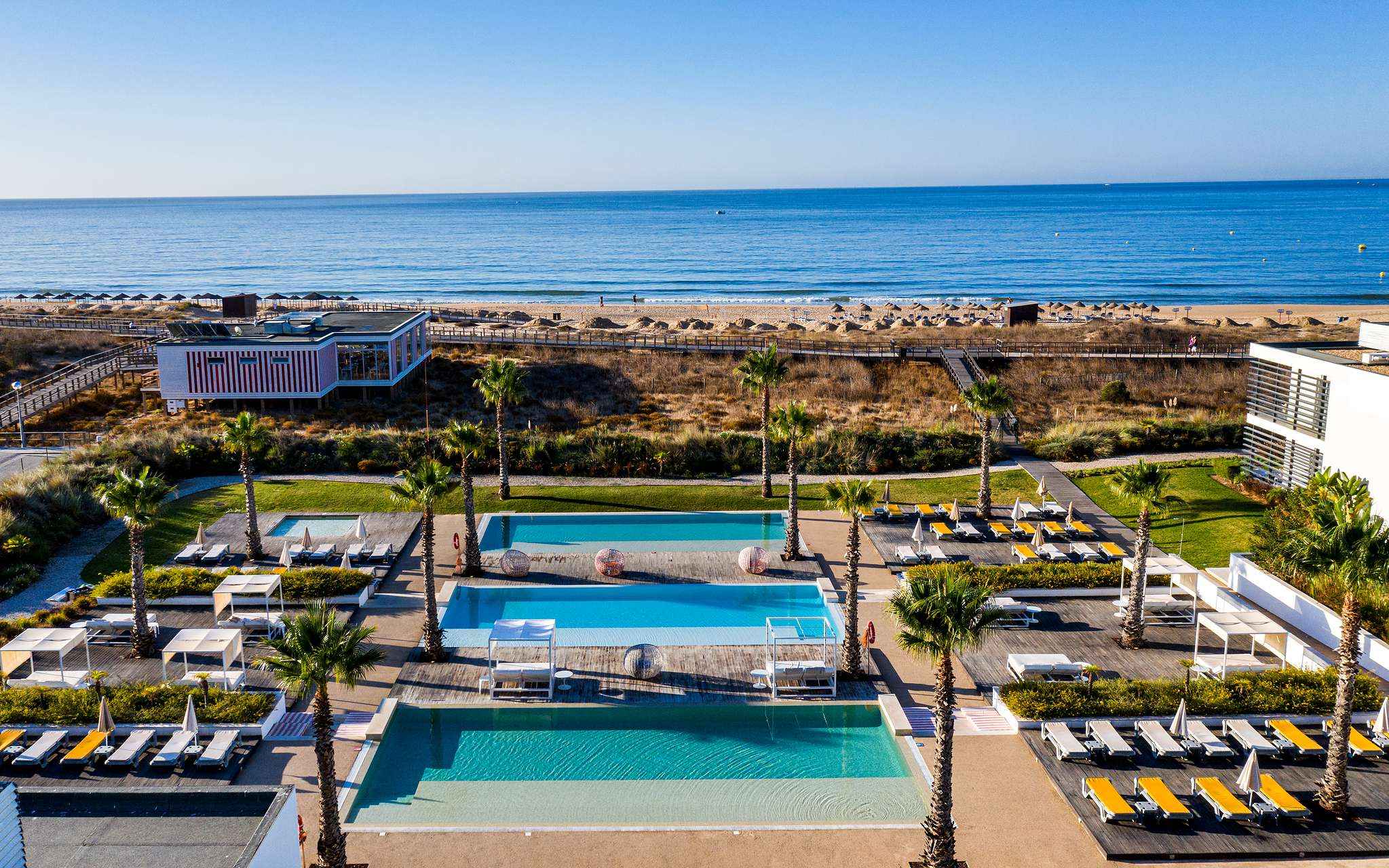 Zone extérieure des piscines et transats de Pestana Alvor South Beach, avec accès direct à la plage