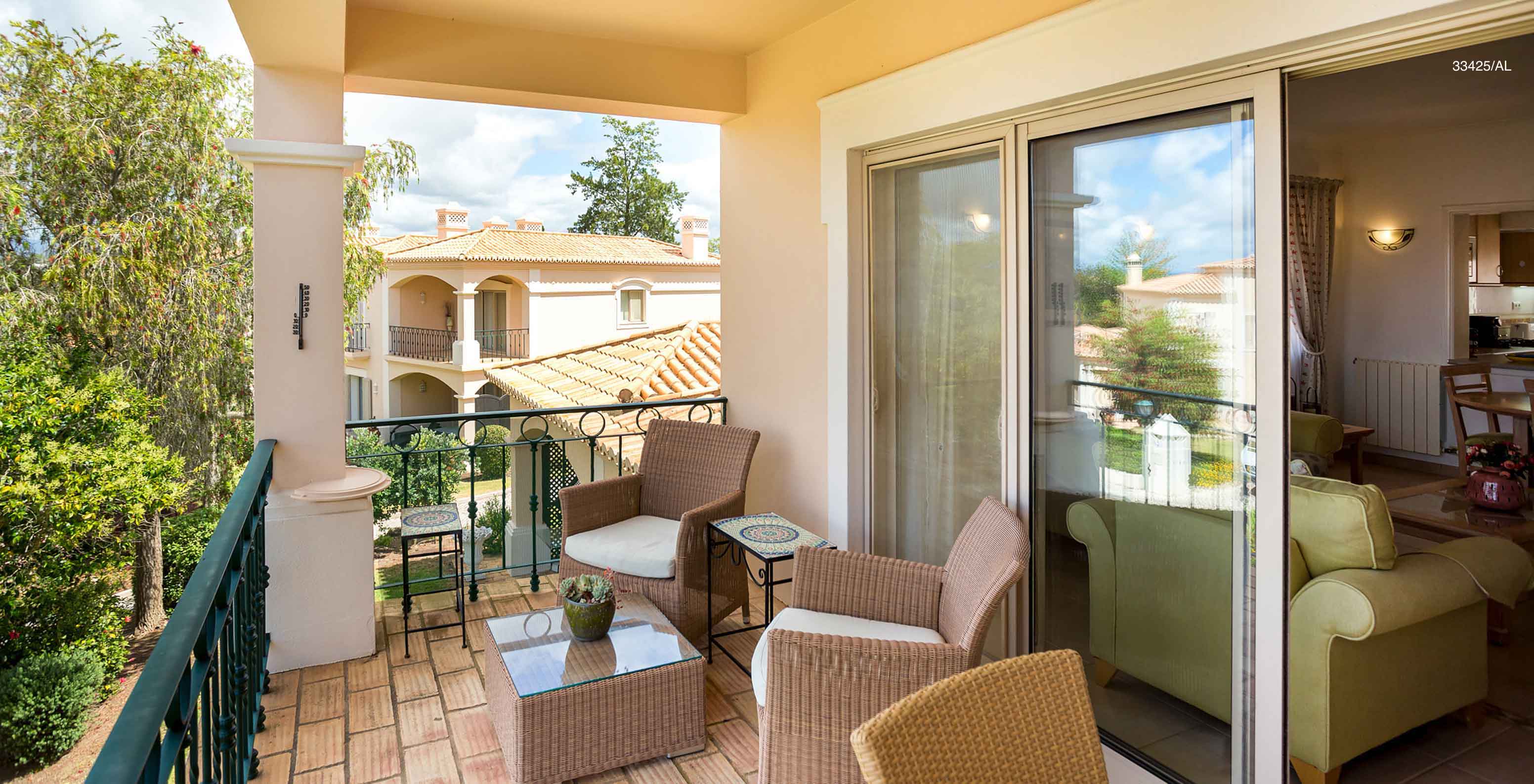 L'appartement Pestana Carvoeiro Golf T2 Standard dispose d'un balcon avec une table, deux chaises et une vue sur le jardin
