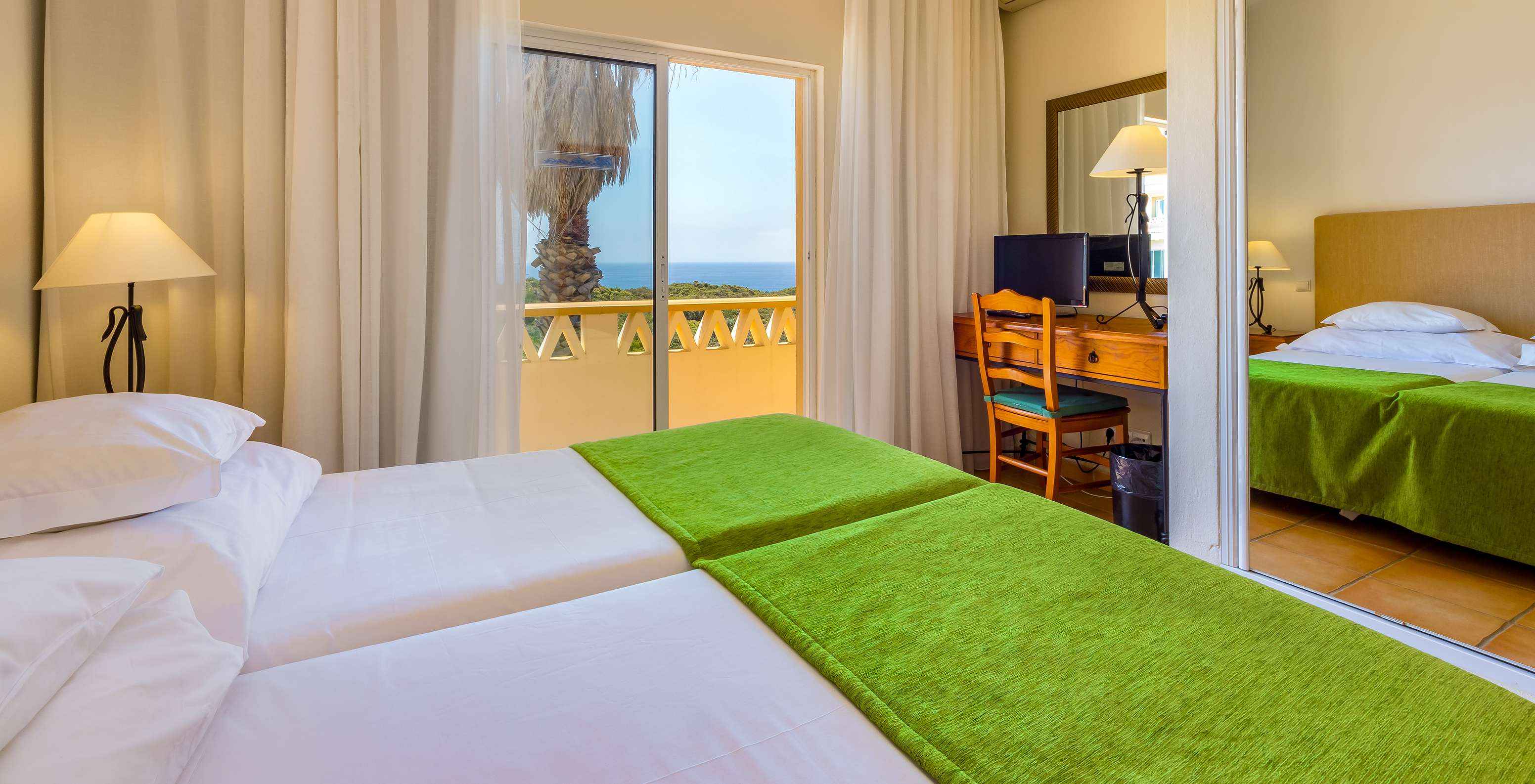 L'Appartement T2 Premium du Pestana Palm Gardens a deux lits avec couvre-lit vert et un balcon avec vue sur la mer