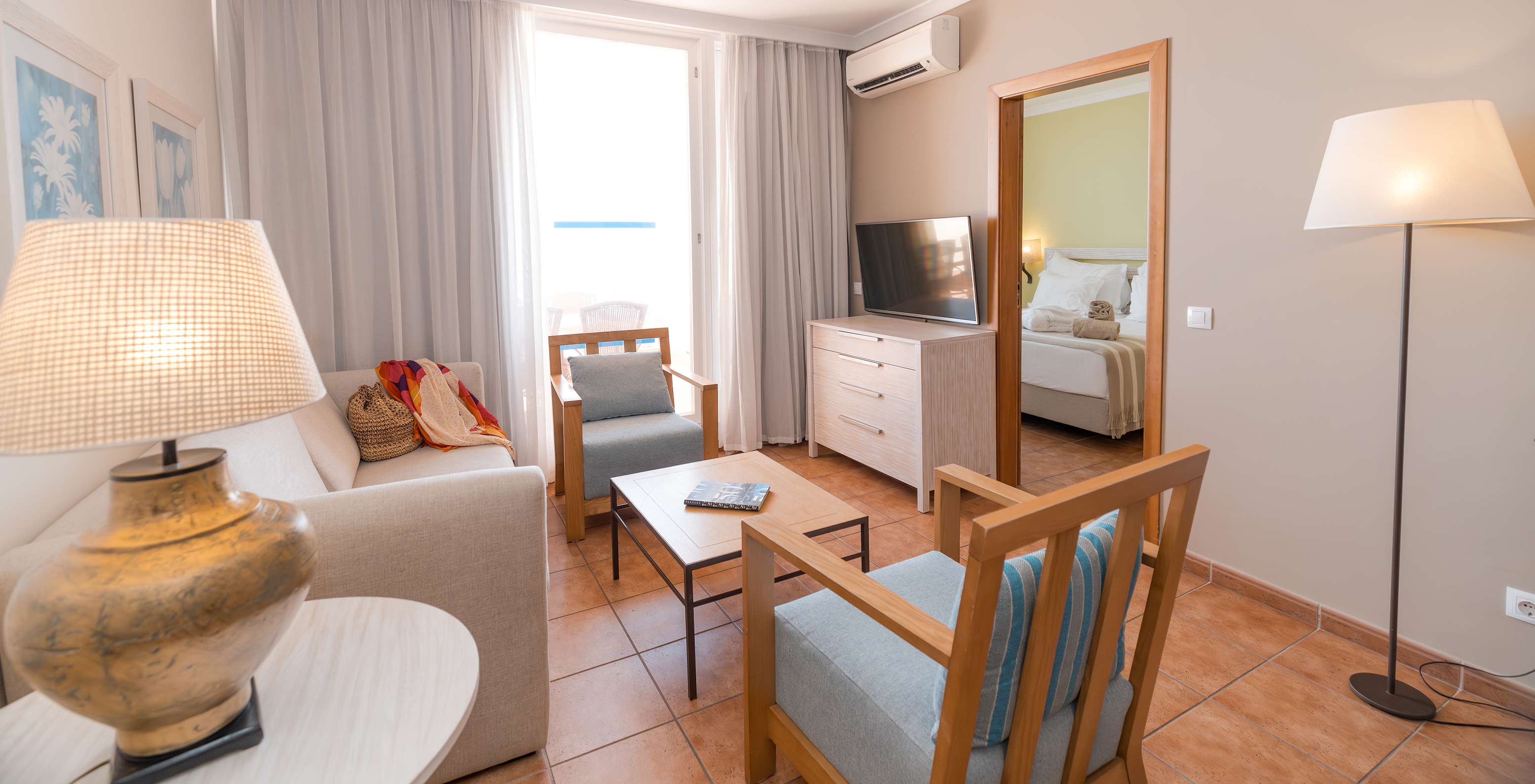 La Suite Vue Mer du Pestana Viking a un salon avec canapé, fauteuils, télévision, climatisation et accès au balcon