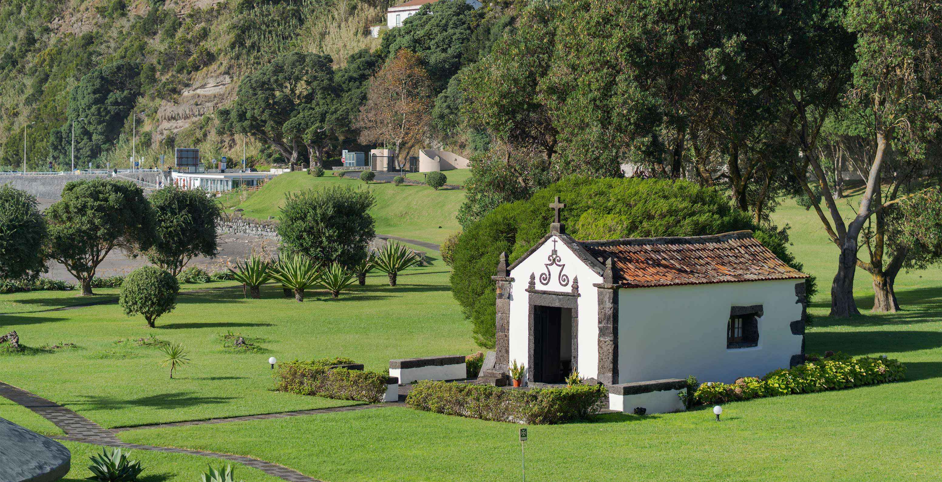 Chapelle à l'extérieur de l'hôtel au milieu de jardins verdoyants et chemins pour se promener