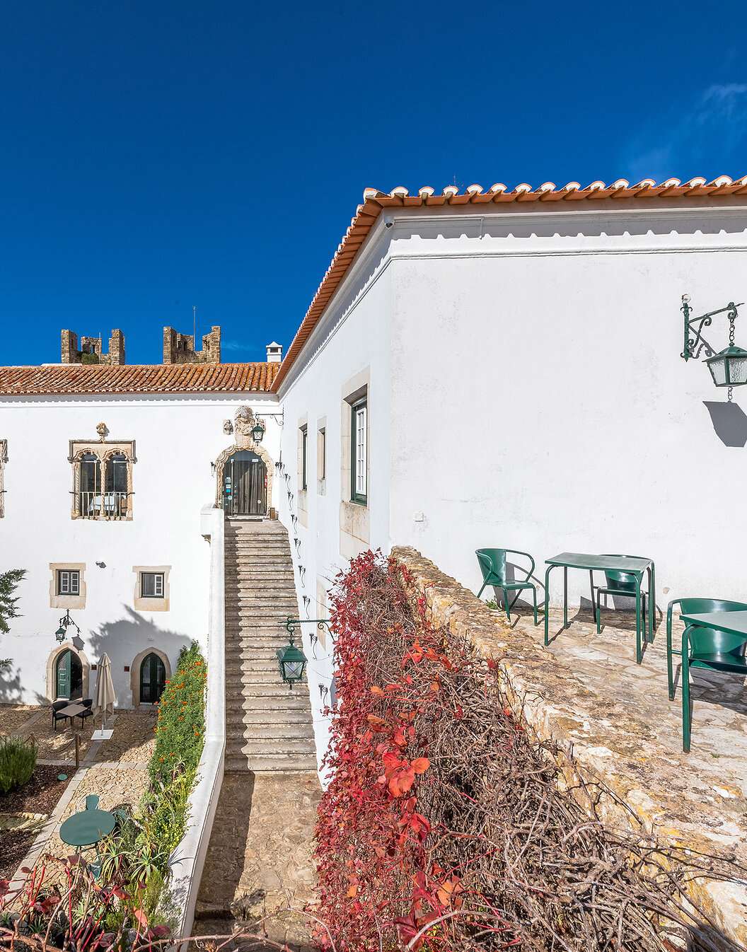Vue extérieure de la façade de la Pousada Castelo Óbidos, avec ses jardins, chaises et tables autour