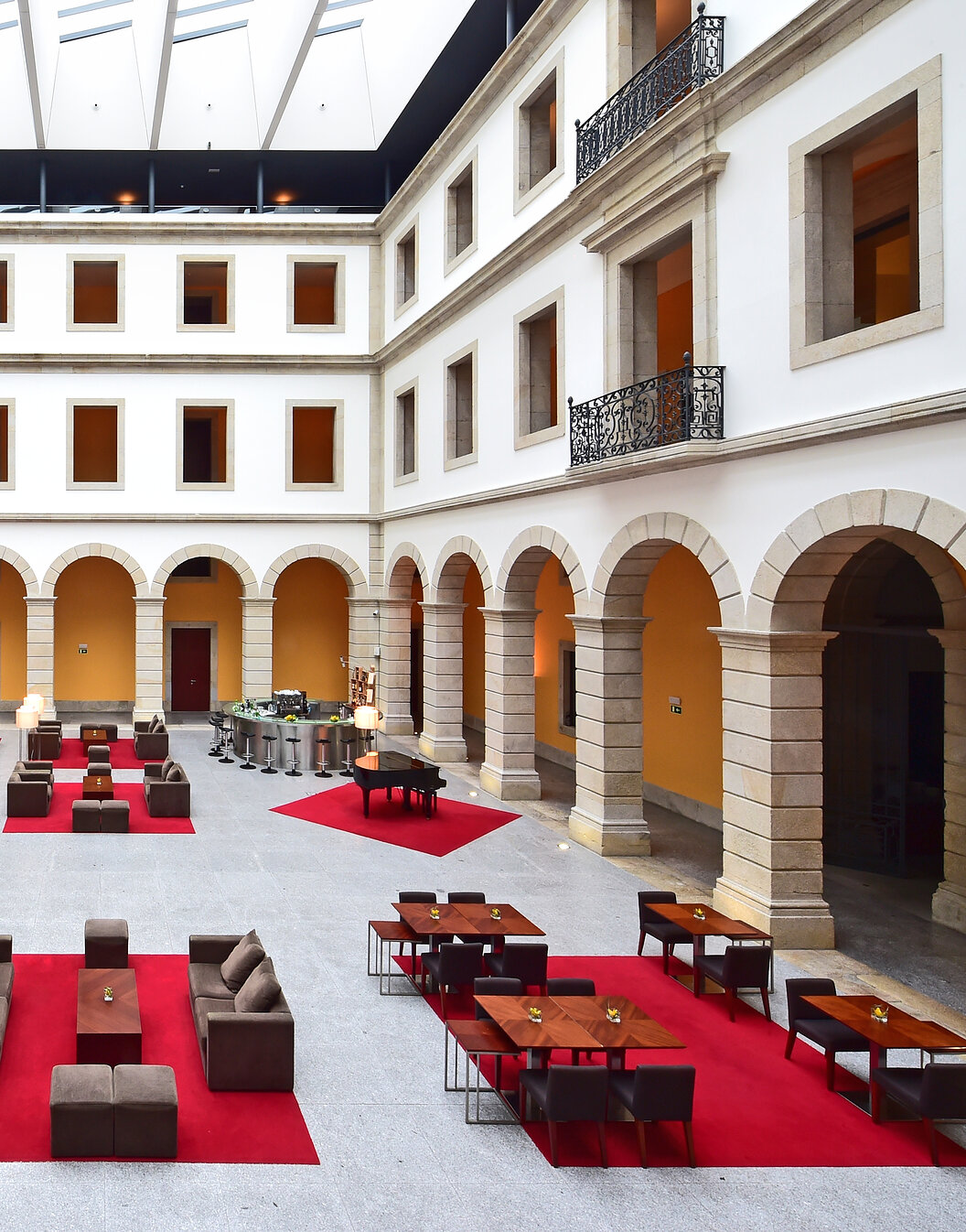 Patio intérieur de la Pousada Viseu, hôtel historique à Viseu, avec des arches autour et plusieurs canapés et bancs