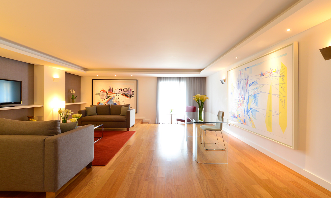 La Suite Présidentielle du Pestana Cidadela Cascais a un salon avec un bureau transparent, des tableaux et un canapé