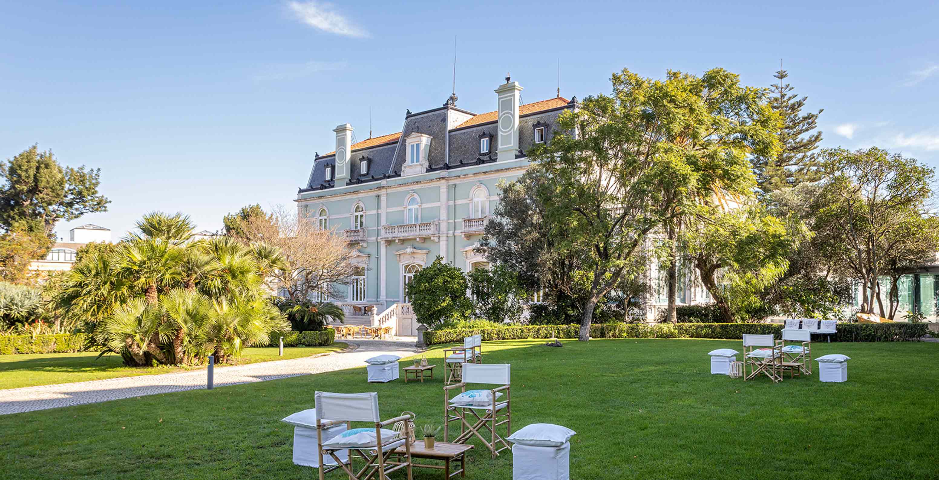 Le Pestana Palace Lisboa a un jardin avec tables et chaises sur pelouse verte, près du bâtiment principal
