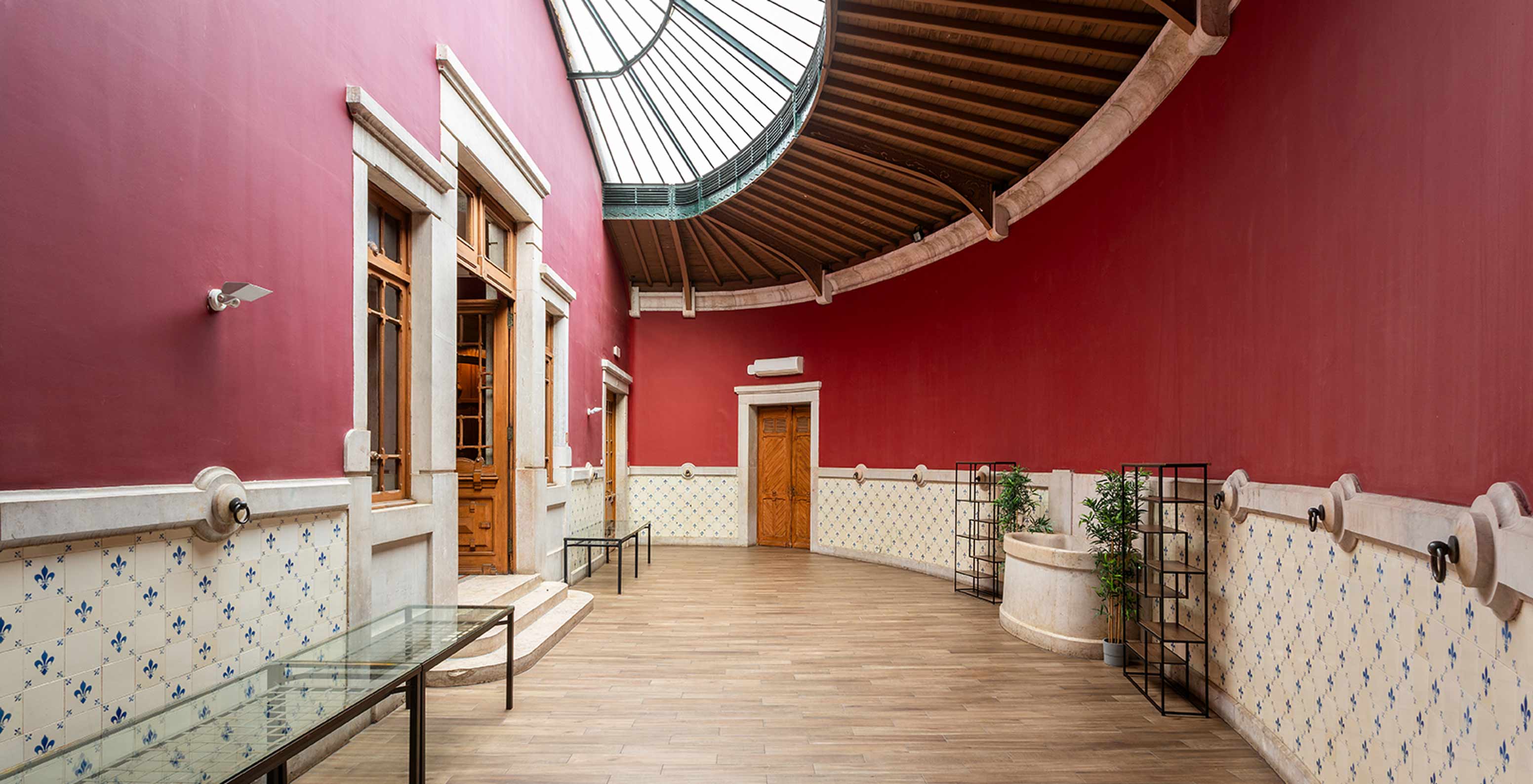 Le Pestana Palace Lisboa a une salle d'événements avec murs rouges et azulejos bleus et blancs, décorée de plantes	