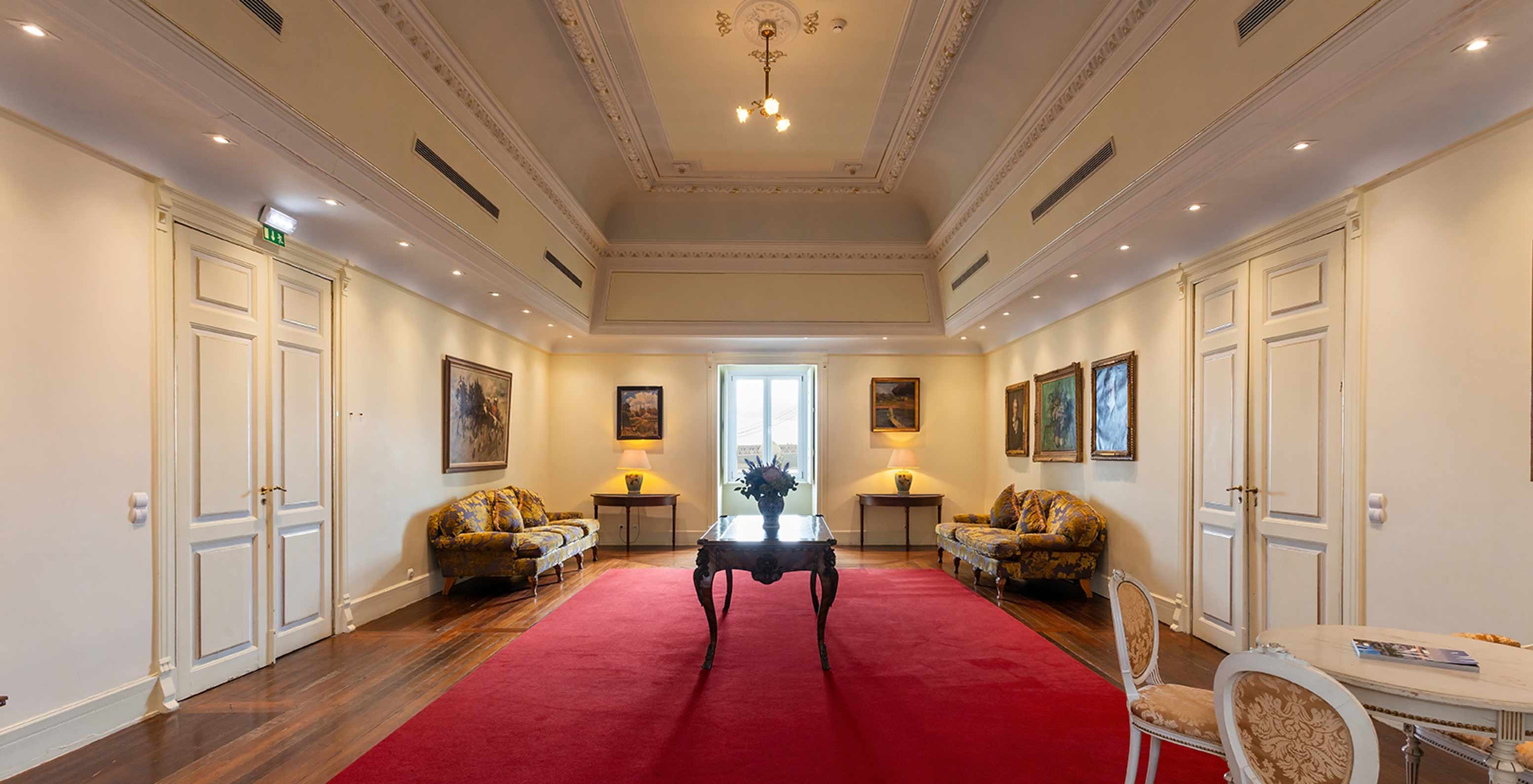 Le Pestana Palace Lisboa a un foyer avec grande moquette rouge, deux canapés et une fenêtre dans le coin