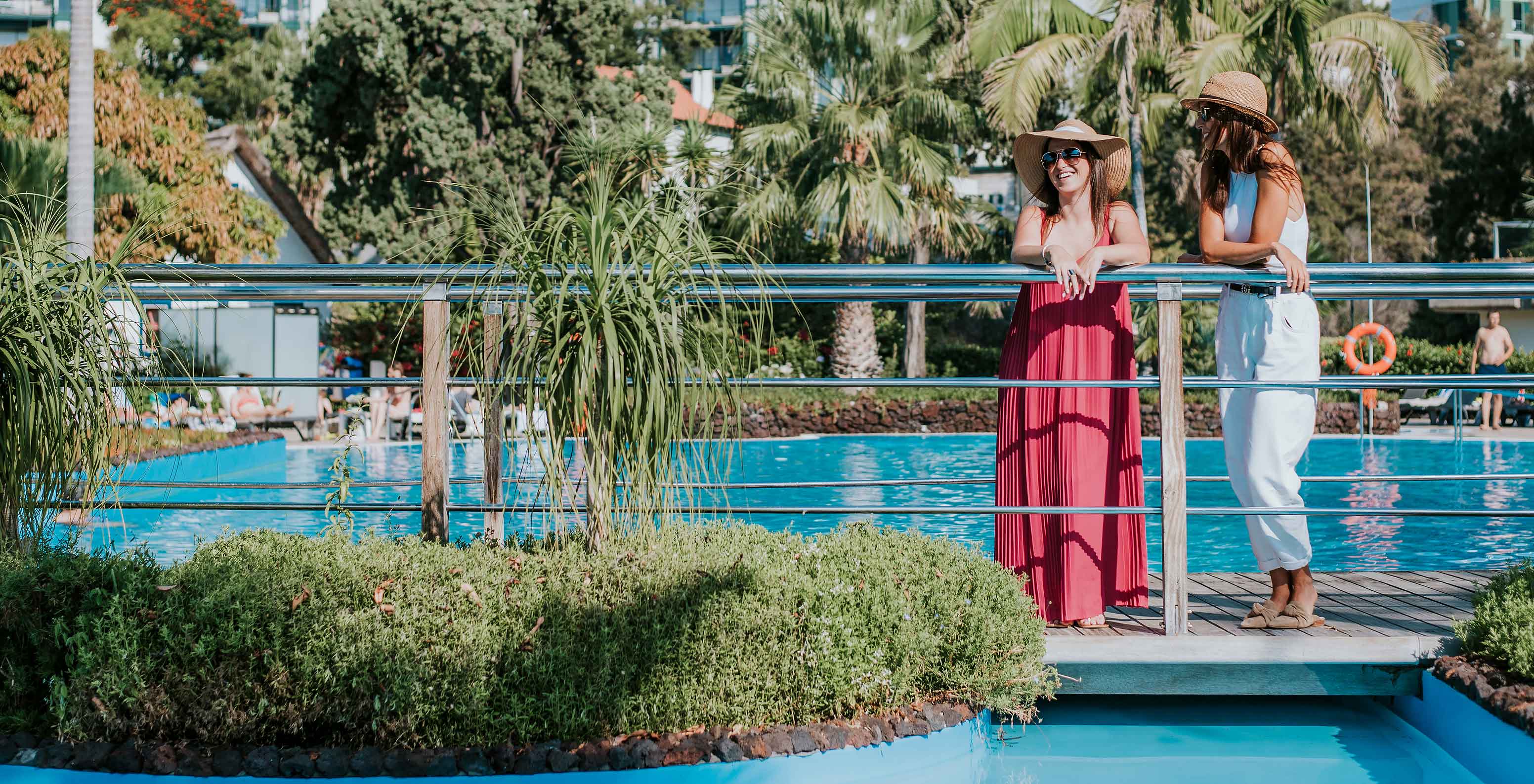 Piscine extérieure du Pestana Carlton Madeira, avec deux filles souriantes appréciant la vue, entourée de verdure