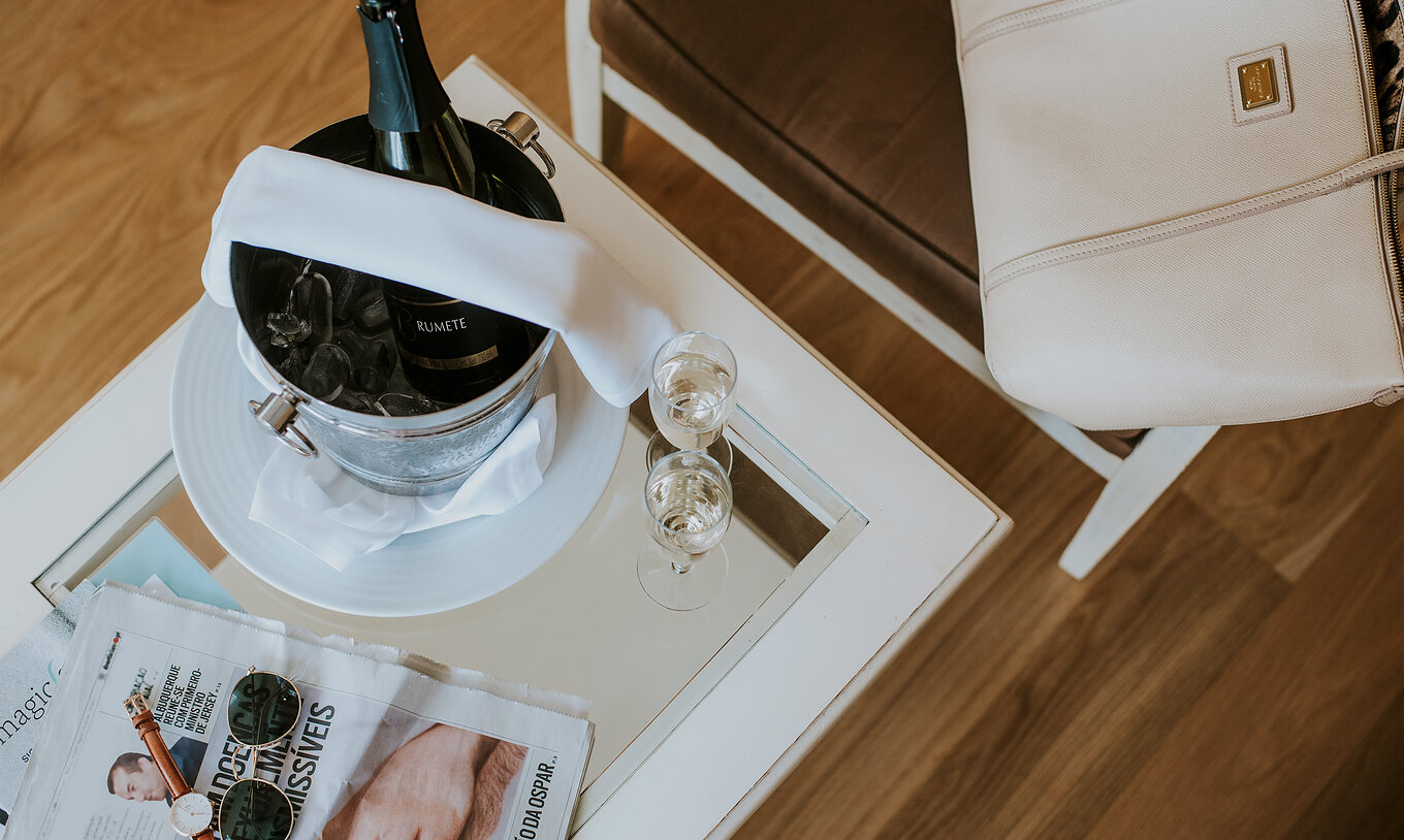 L'appartement T2 du Pestana Madeira Beach Club a une table avec champagne, journaux et une chaise