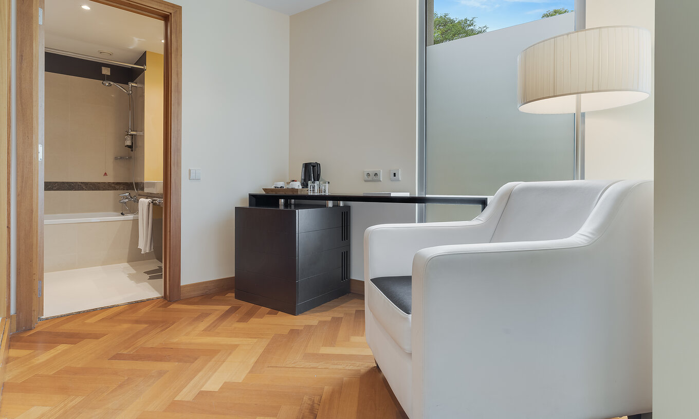 Le Twin Classique du Pestana Promenade a une salle de bain avec baignoire et a un fauteuil et une table à l'entrée